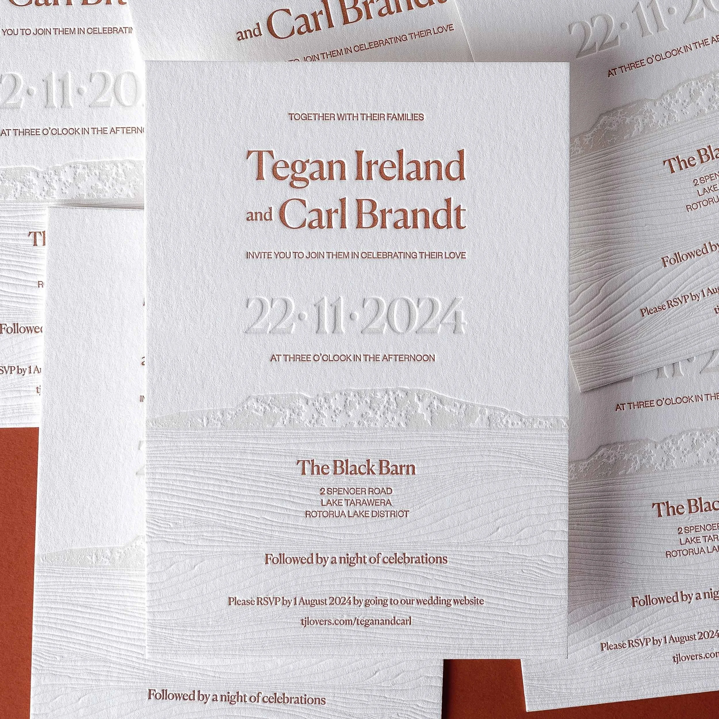 Close-up of Tegan and Carl's letterpress wedding invitation, showing the debossed Mount Tarawera landscape and textured lines inspired by Lake Tarawera.