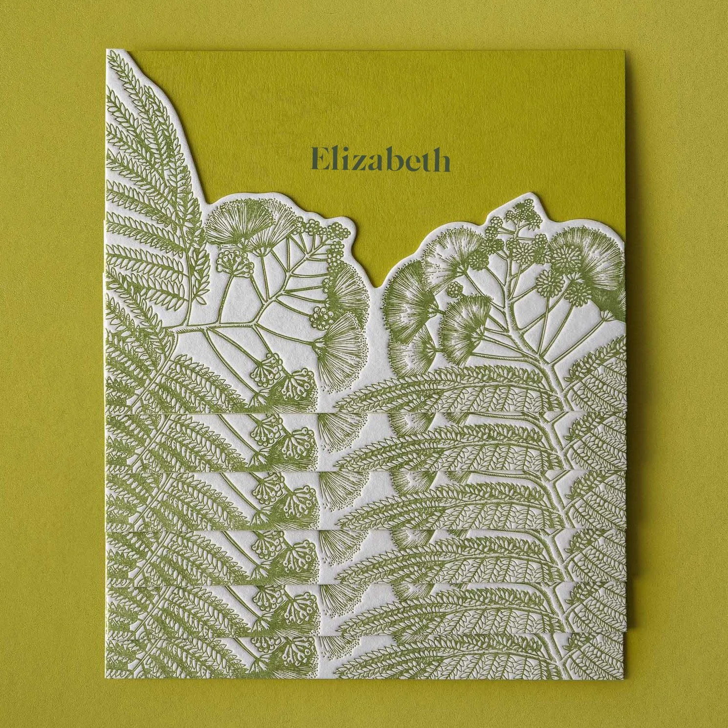 Greer and Cohen’s layered wedding place cards featuring die-cut silk tree flower illustrations letterpress printed in green.