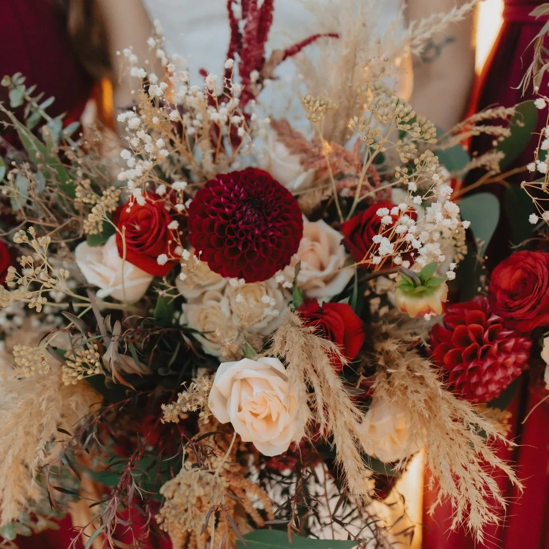 Brontë and Simon’s wedding florals at Boomrock, with deep burgundy flowers, soft neutrals and feathery dried grasses.