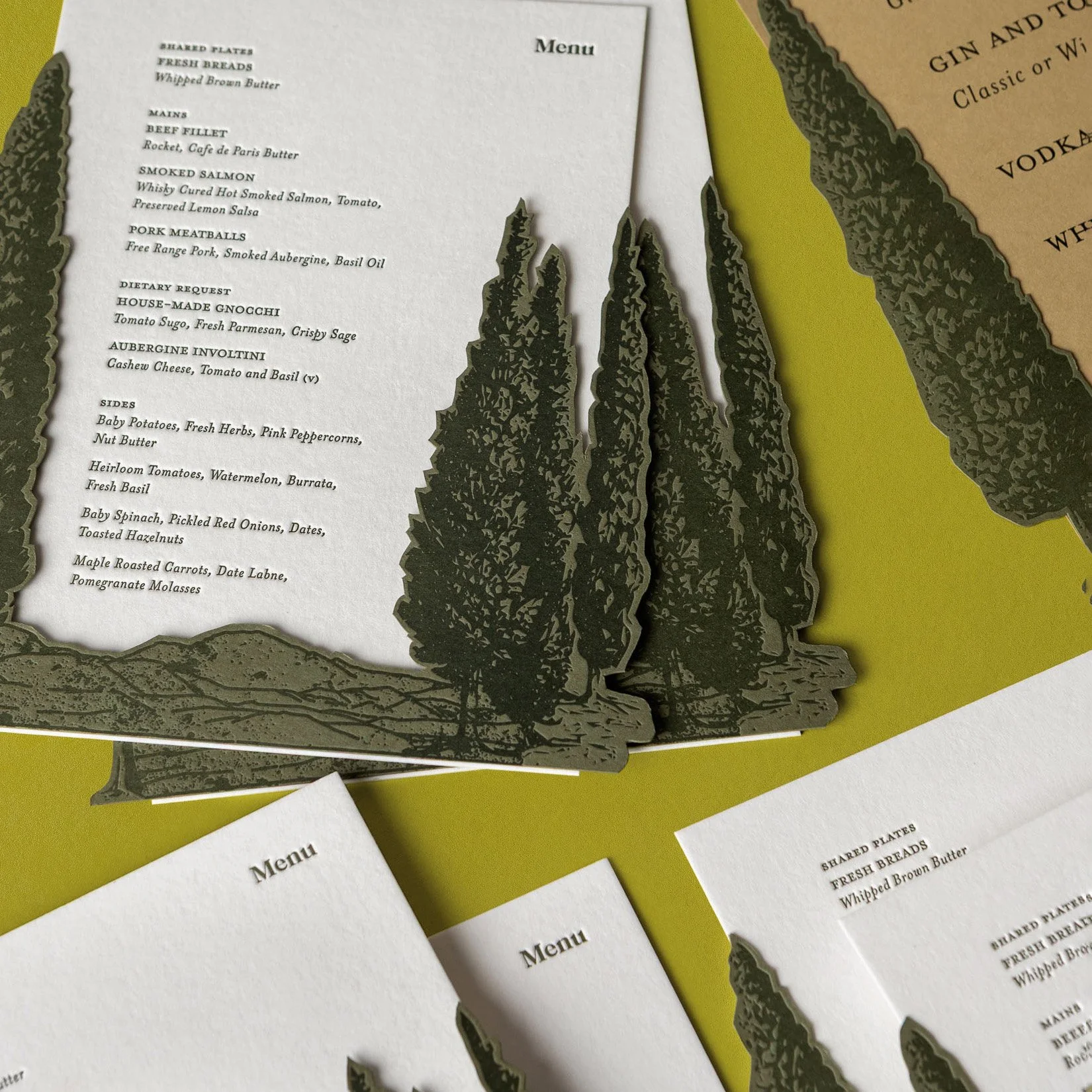 Greer and Cohen’s wedding dinner menus featuring layered die-cut letterpress conifers on cotton card.