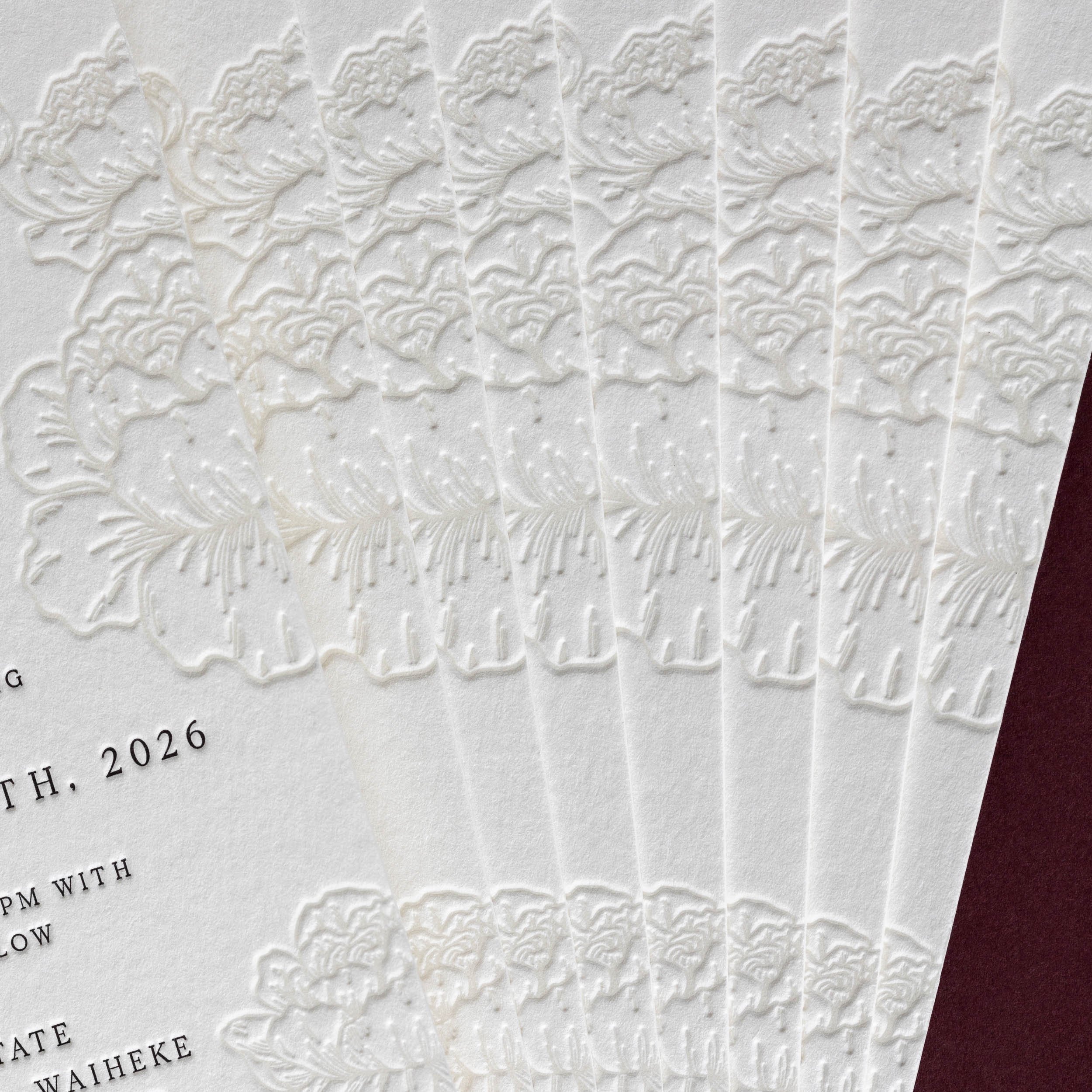 Close-up of repeated deep letterpress peony impressions showing the tactile texture of the printed invitation.