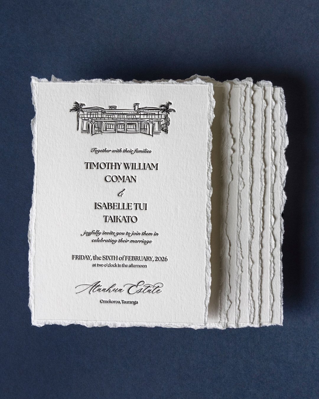 Stack of deckled-edge letterpress wedding invitations featuring an illustration of Ataahua Estate on soft cotton paper.