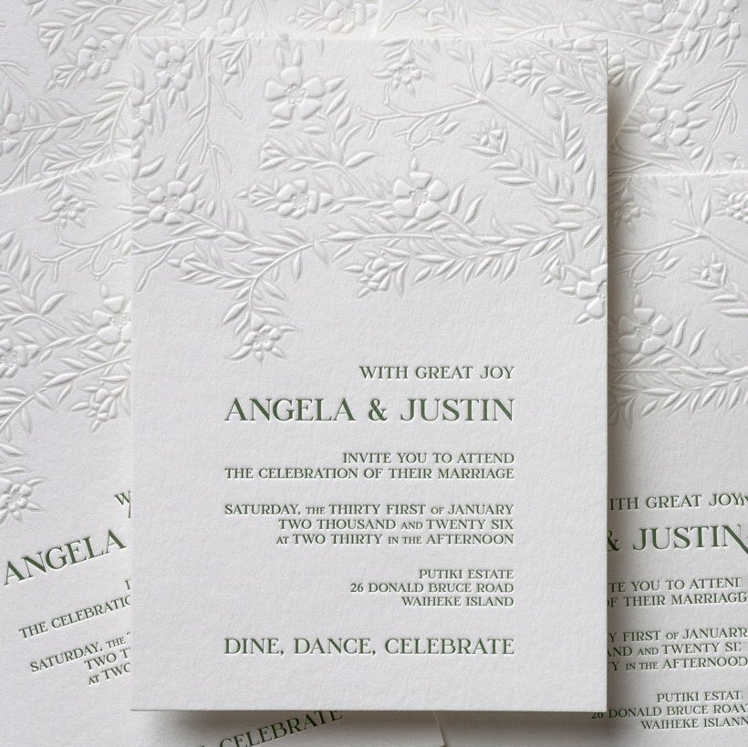Cream wedding invitation with embossed mānuka botanical artwork and green typography for a Putiki Estate wedding.