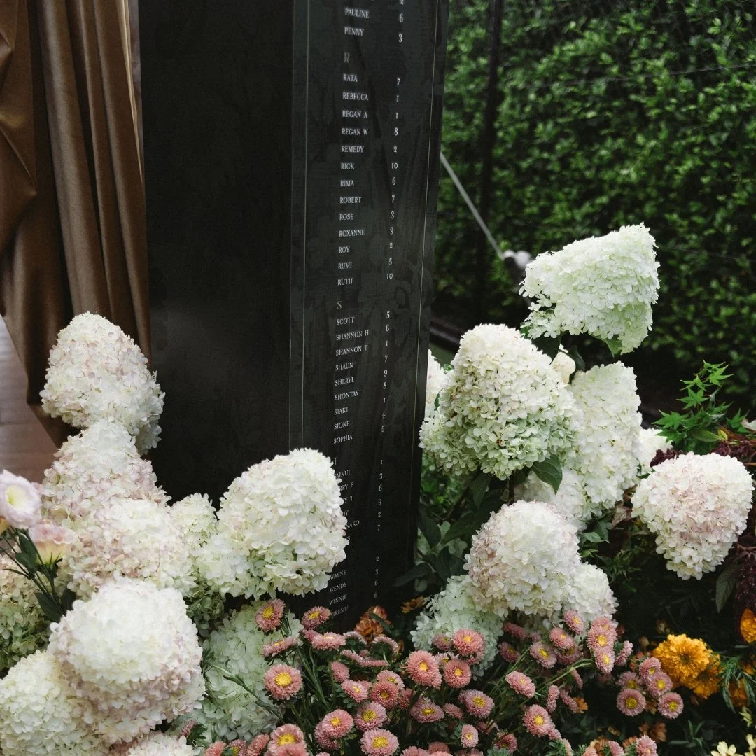 Detail of Angela and Justin’s wedding seating plan at Putiki Estate, featuring tapestry artwork surrounded by florals.