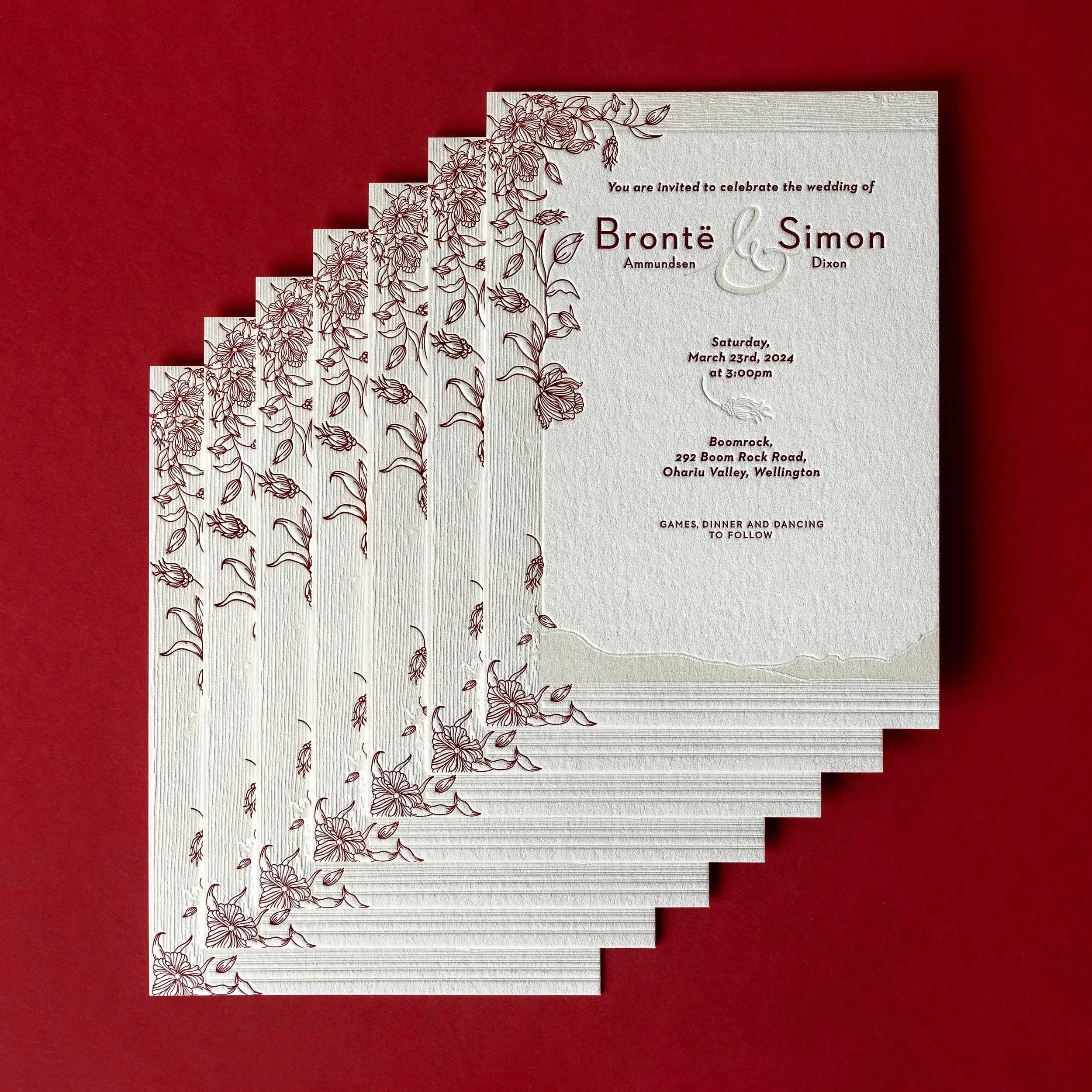 Brontë and Simon’s letterpress wedding invitations with burgundy floral artwork and an embossed Boomrock landscape.