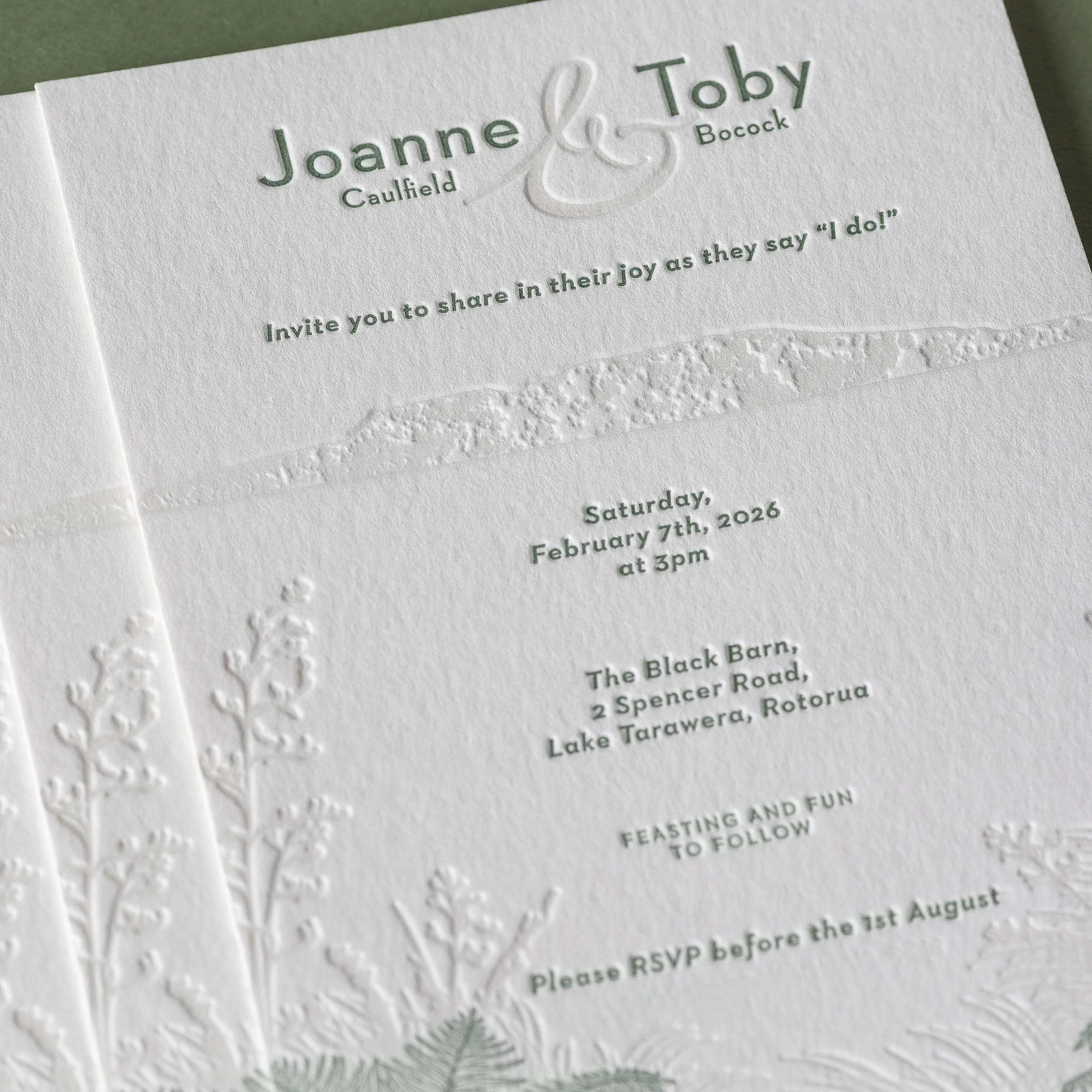 Close-up of a letterpress wedding invitation featuring a custom illustration of Mt Tarawera and native New Zealand flora.