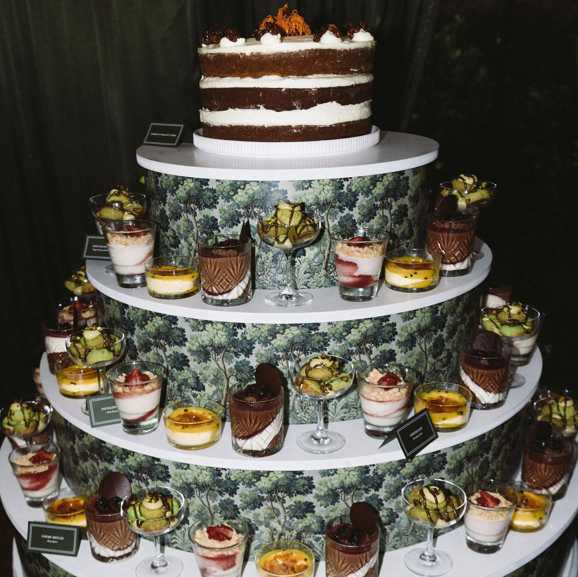 Angela and Justin’s wedding dessert stand at Putiki Estate, featuring tapestry artwork and deep green tent-fold dessert cards printed in white ink.