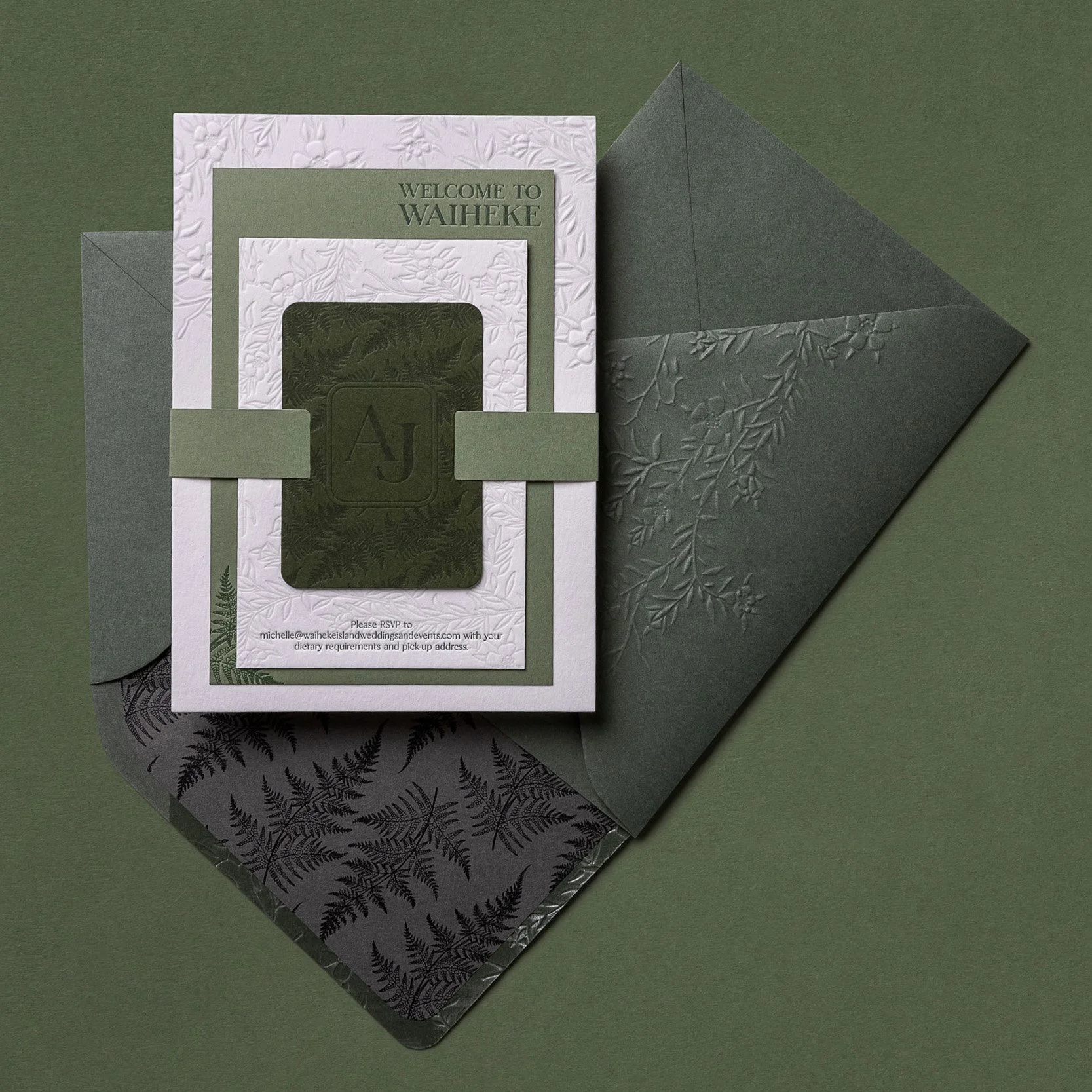 Green and cream wedding invitation suite with embossed mānuka envelope and fern-patterned envelope liner.