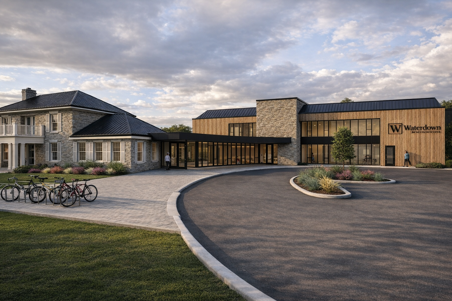 Modern building with stone and wood exterior, glass entrance, and a sign that reads 'Waterdown Architecture' on the right side. Bicycles are parked on the left, and a few people are walking near the entrance under a partly cloudy sky.