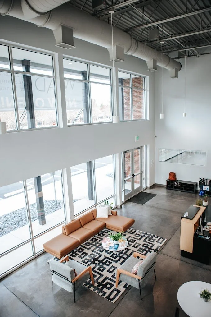 Bright and modern lobby with floor-to-ceiling windows, lounge seating, and geometric rugs. Highlights a welcoming entry space with natural light and contemporary design.