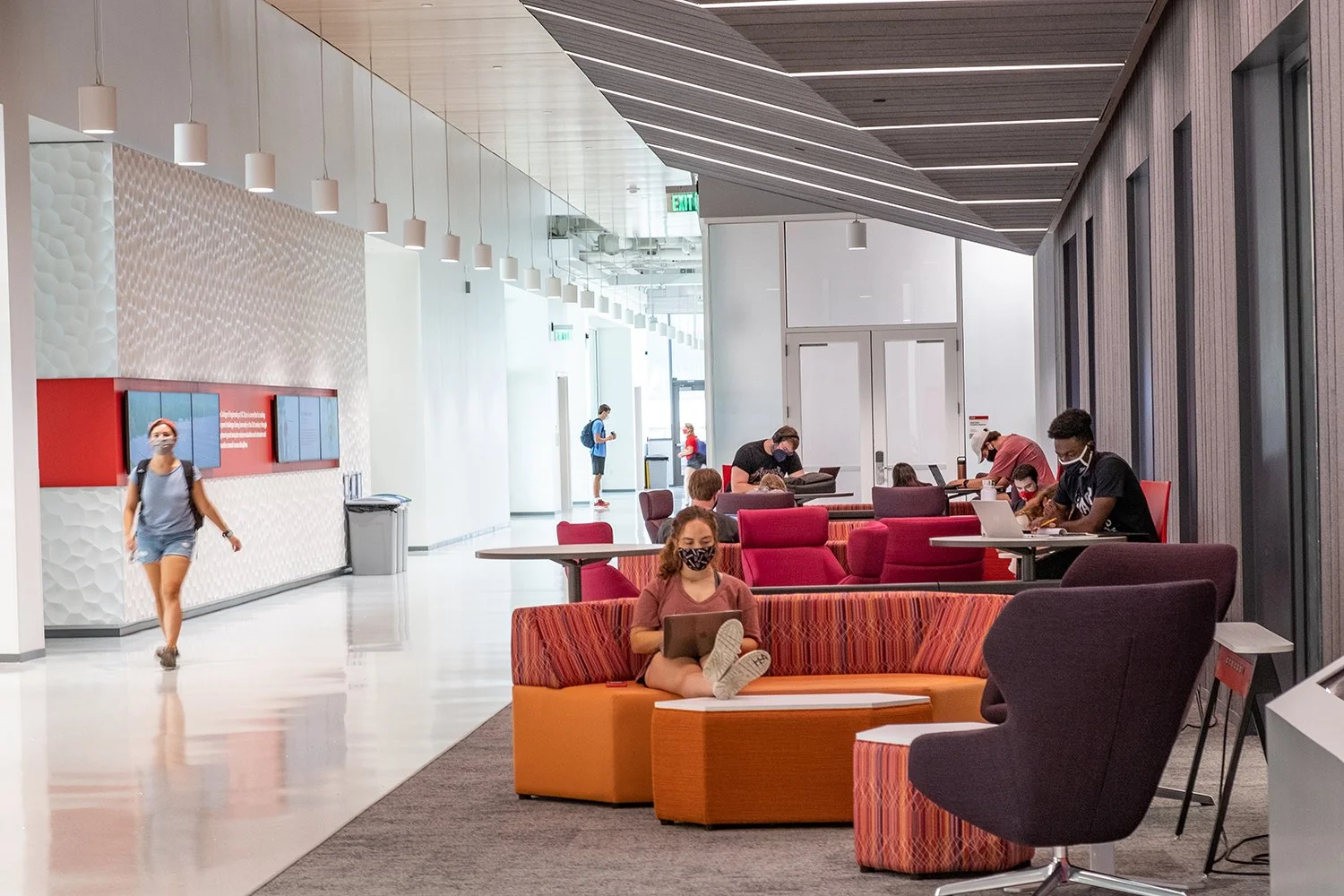 Student lounge with colorful modular seating, sleek lighting, and active study areas. Emphasizes comfort, collaboration, and thoughtful interior design in an academic setting.