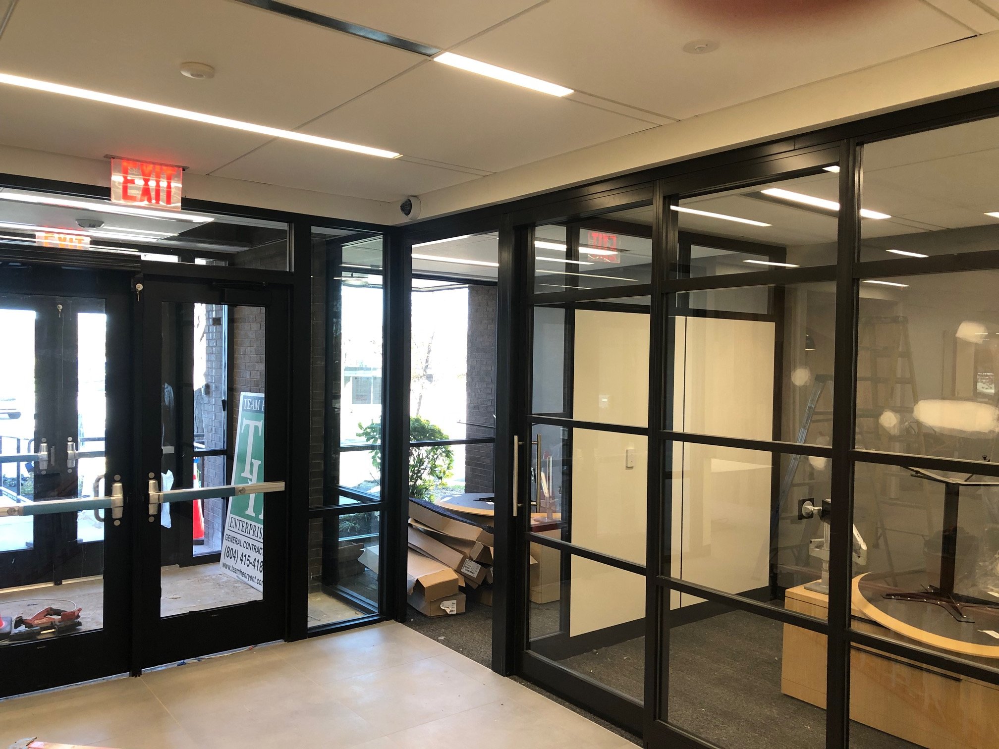 View of a nearly completed Chase bank interior with black-framed glass office partitions and entry doors. Showcases clean, contemporary design with emphasis on transparency and modern functionality.