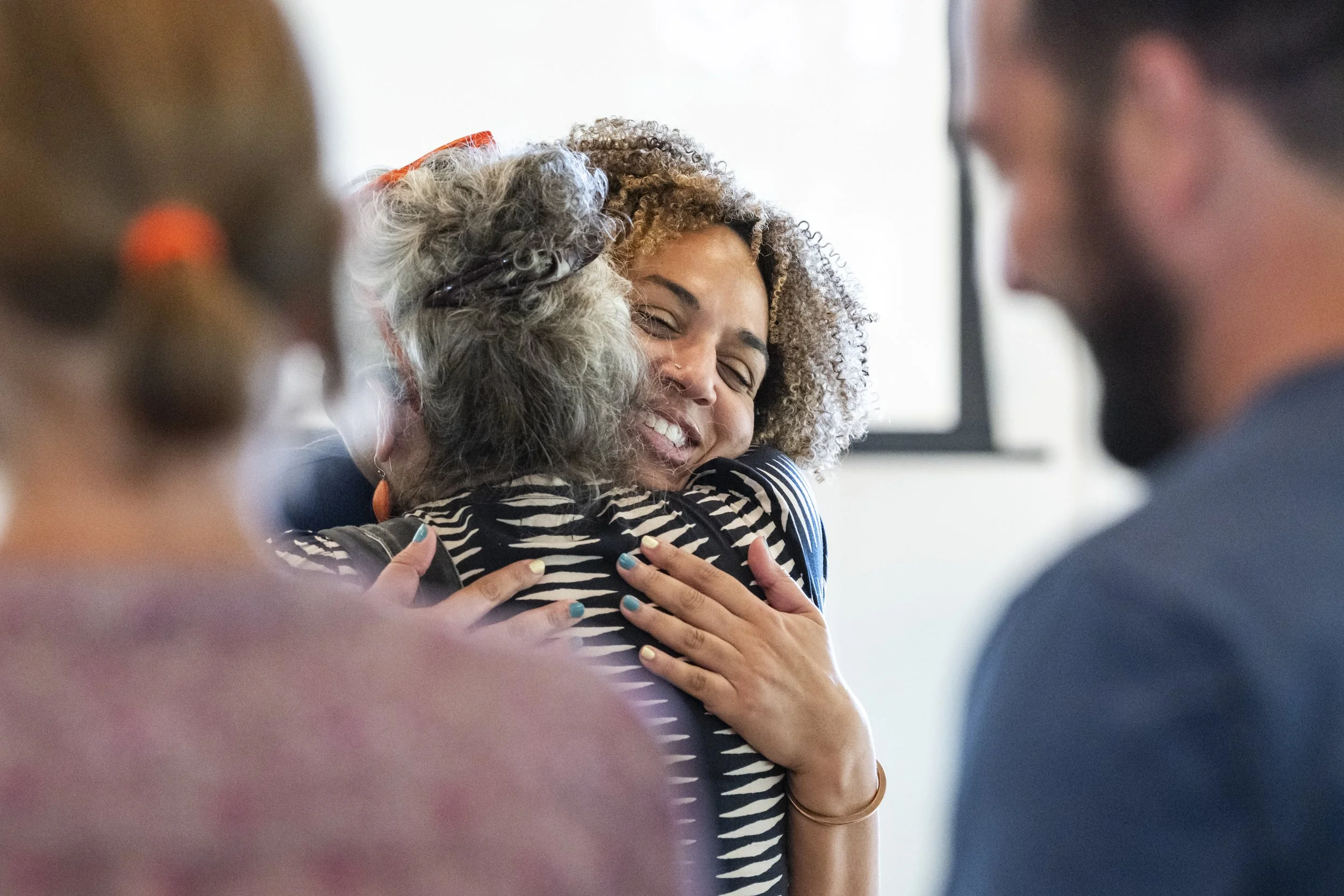 A group of diverse people embracing and smiling at each other in a friendly hug.