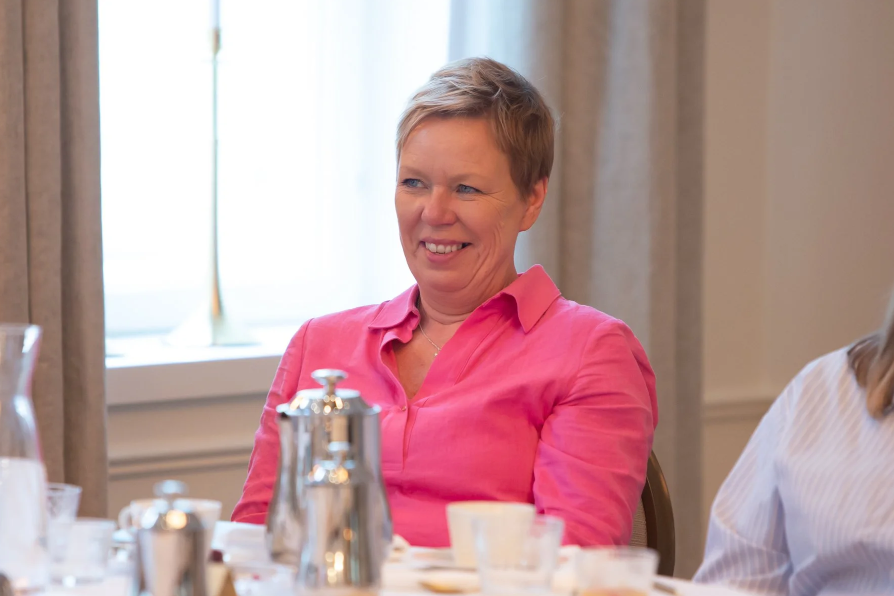 Naisten iloinen keskustelu ruokapöydässä.