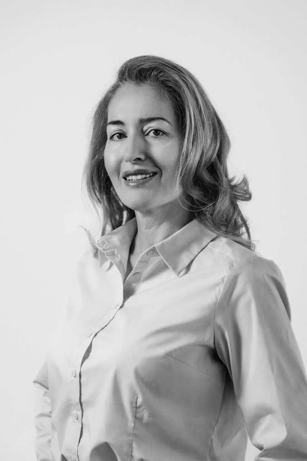 Portræt af en kvinde i lyseblå skjorte på en neutral baggrund.