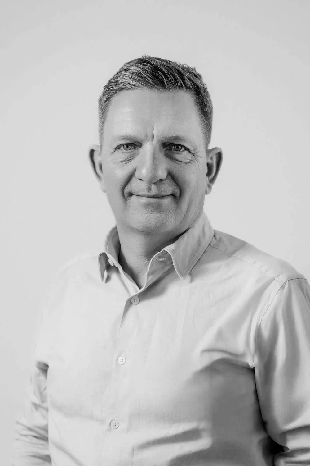 Portræt af en mand i lyseblå skjorte på en neutral baggrund.