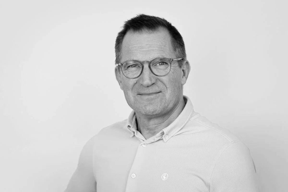 Portræt af en mand i lyseblå skjorte på en neutral baggrund.