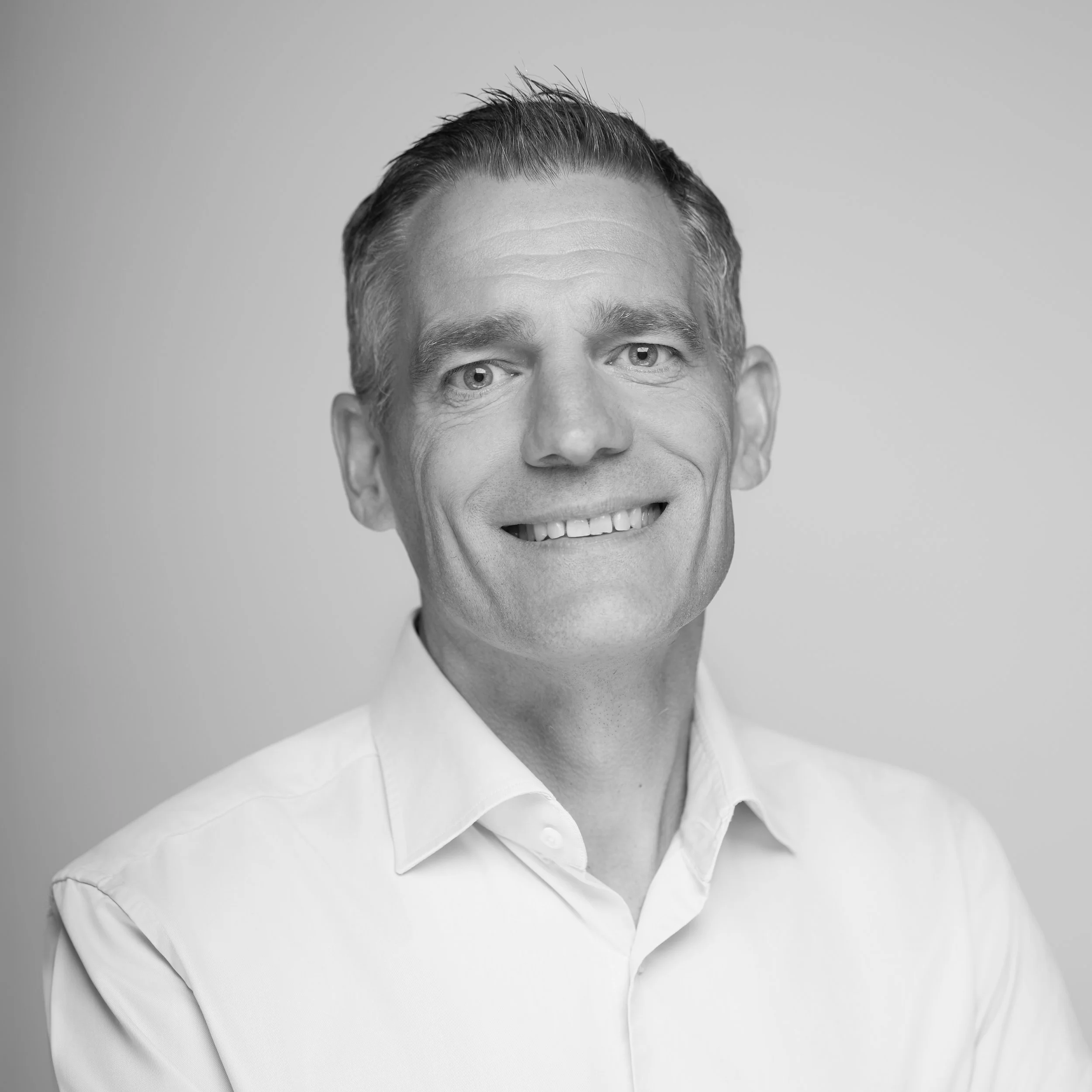Portrait of a man in a light blue shirt on a neutral background.