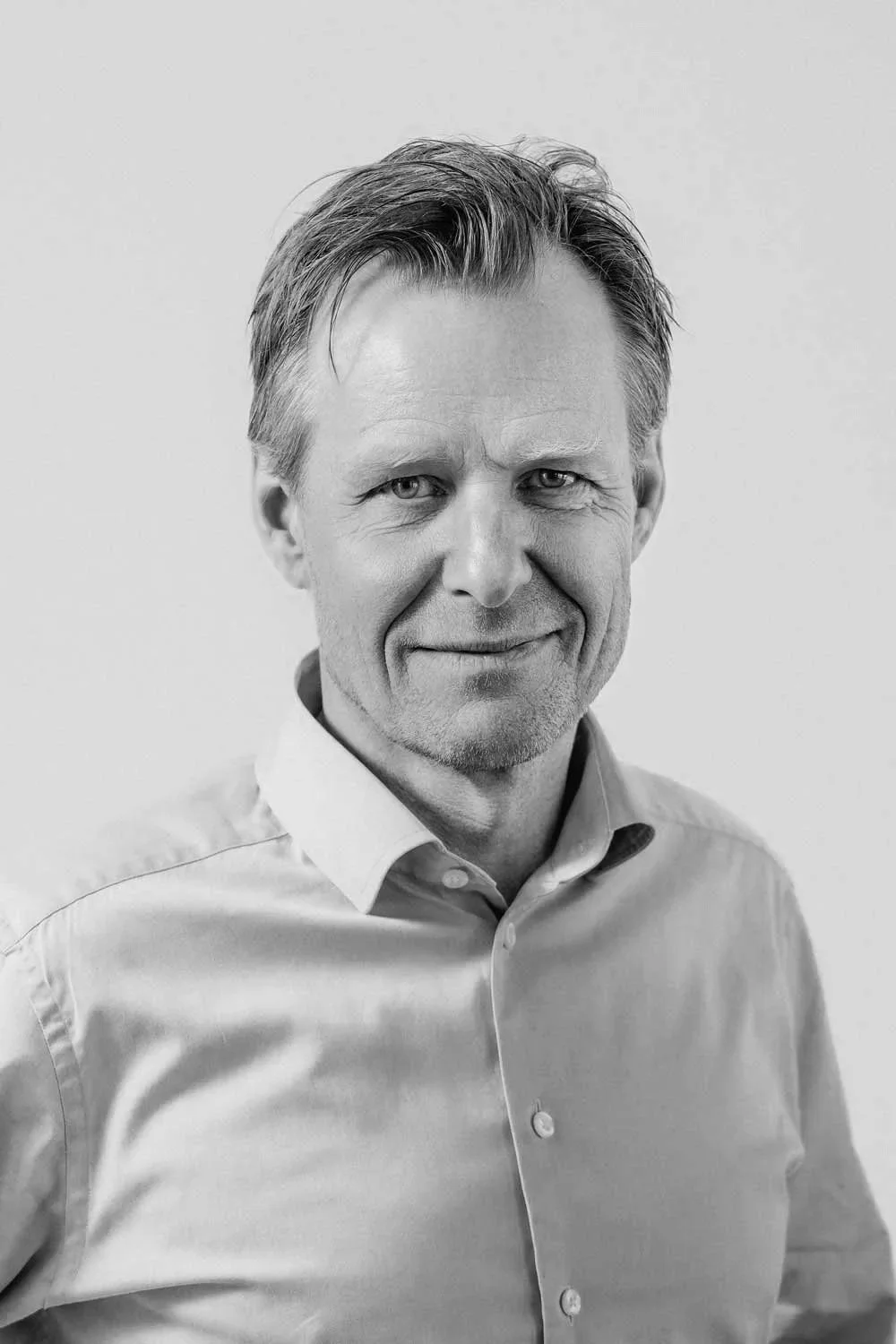 Portræt af en mand i lyseblå skjorte på en neutral baggrund.