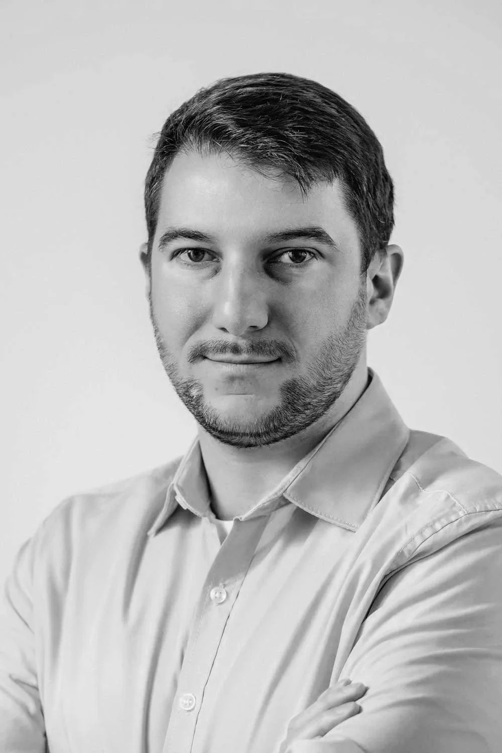 Portræt af en mand i lyseblå skjorte på en neutral baggrund.