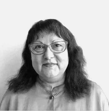 Portræt af en kvinde i lyseblå skjorte på en neutral baggrund.