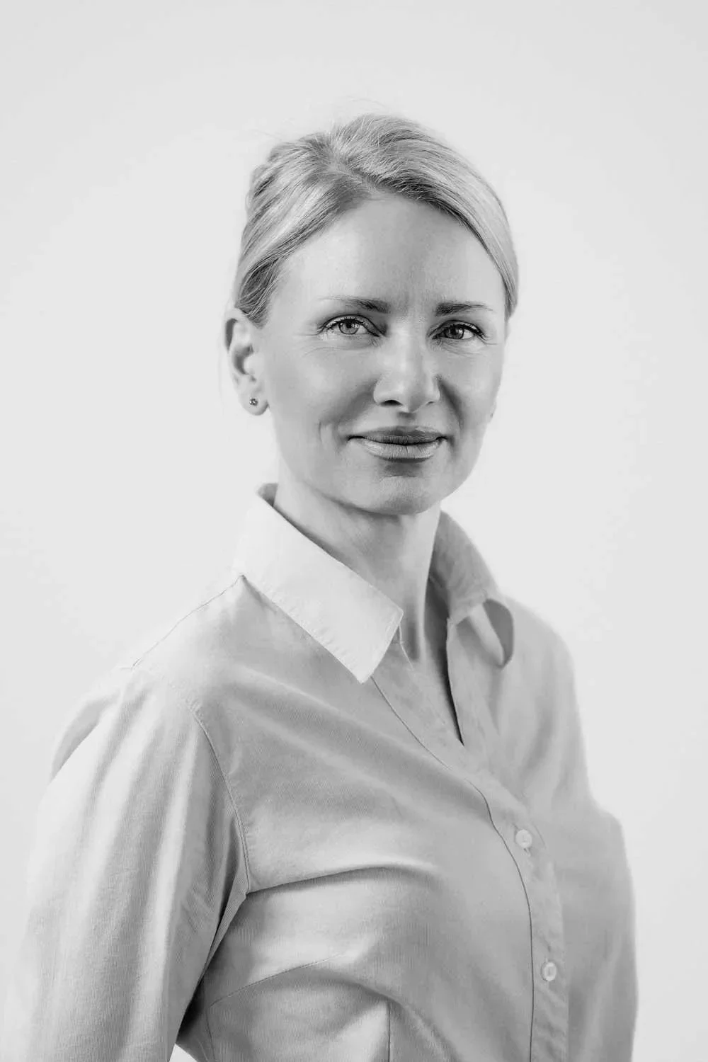 Portræt af en kvinde i lyseblå skjorte på en neutral baggrund.