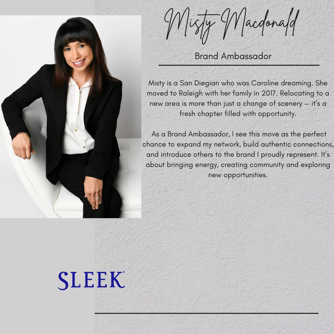 A woman with dark brown hair, wearing a black blazer and white shirt, sitting on a white chair, smiling at the camera.