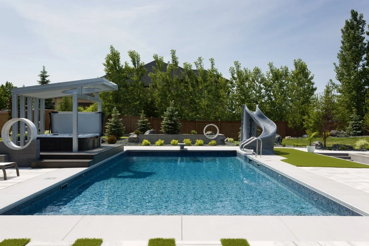 Modern backyard with a swimming pool, waterslide, pergola area, and landscaped garden.