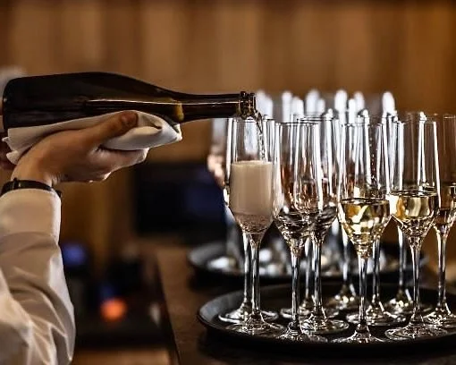 Una mano versa lo champagne in flute su un vassoio con altri bicchieri