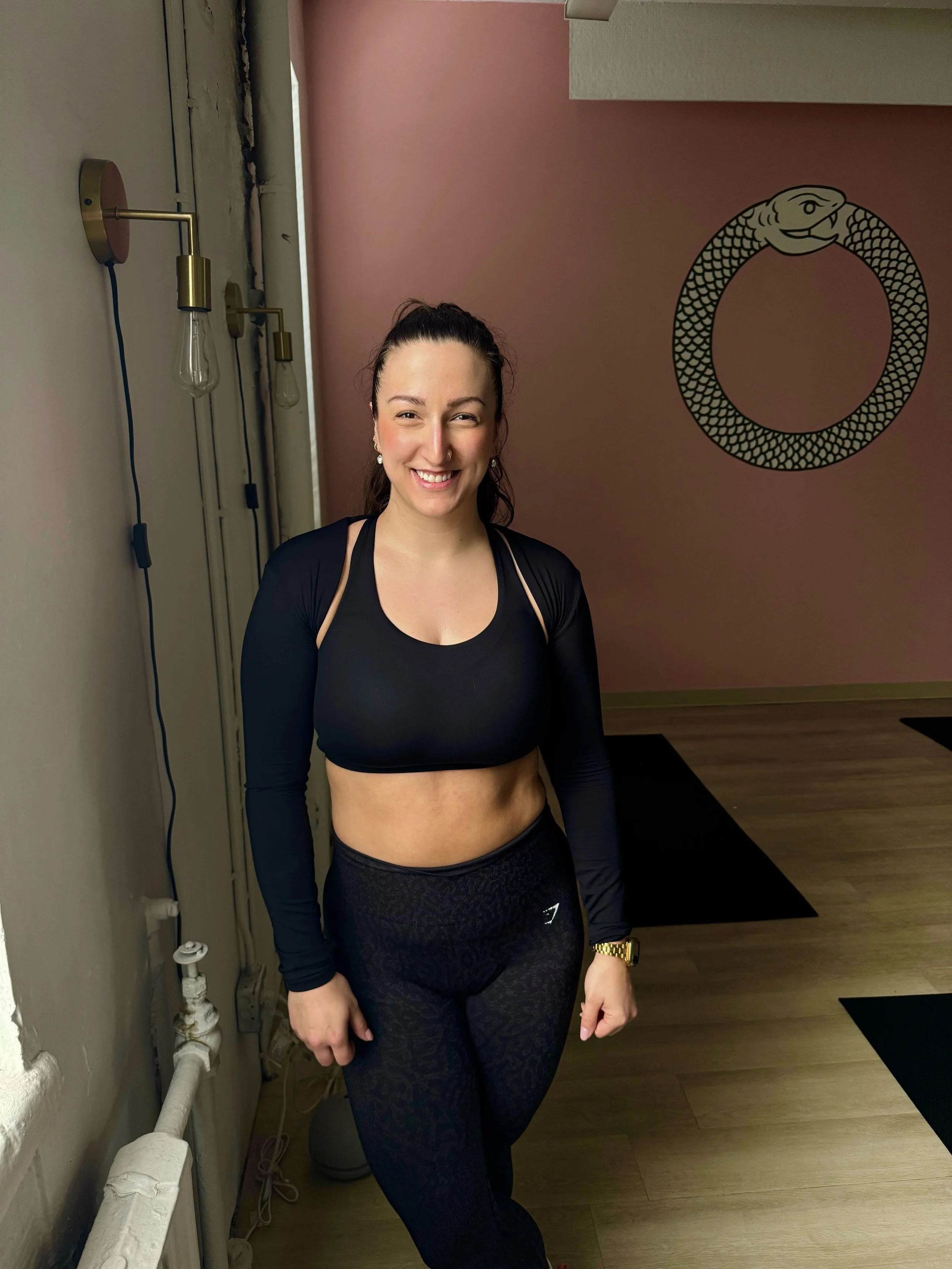 Smiling woman in workout attire inside a gym with wall art