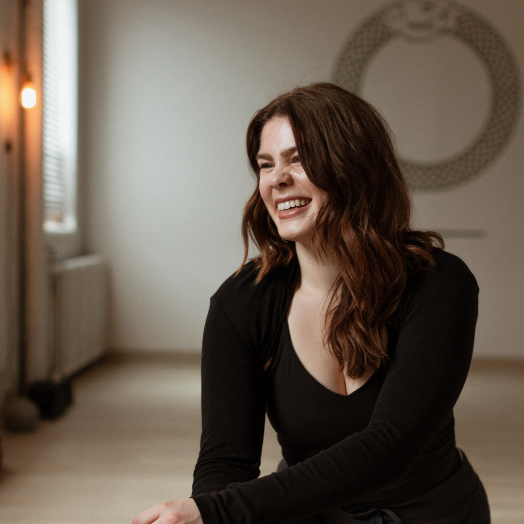 Woman smiling in a bright room with geometric wall art.