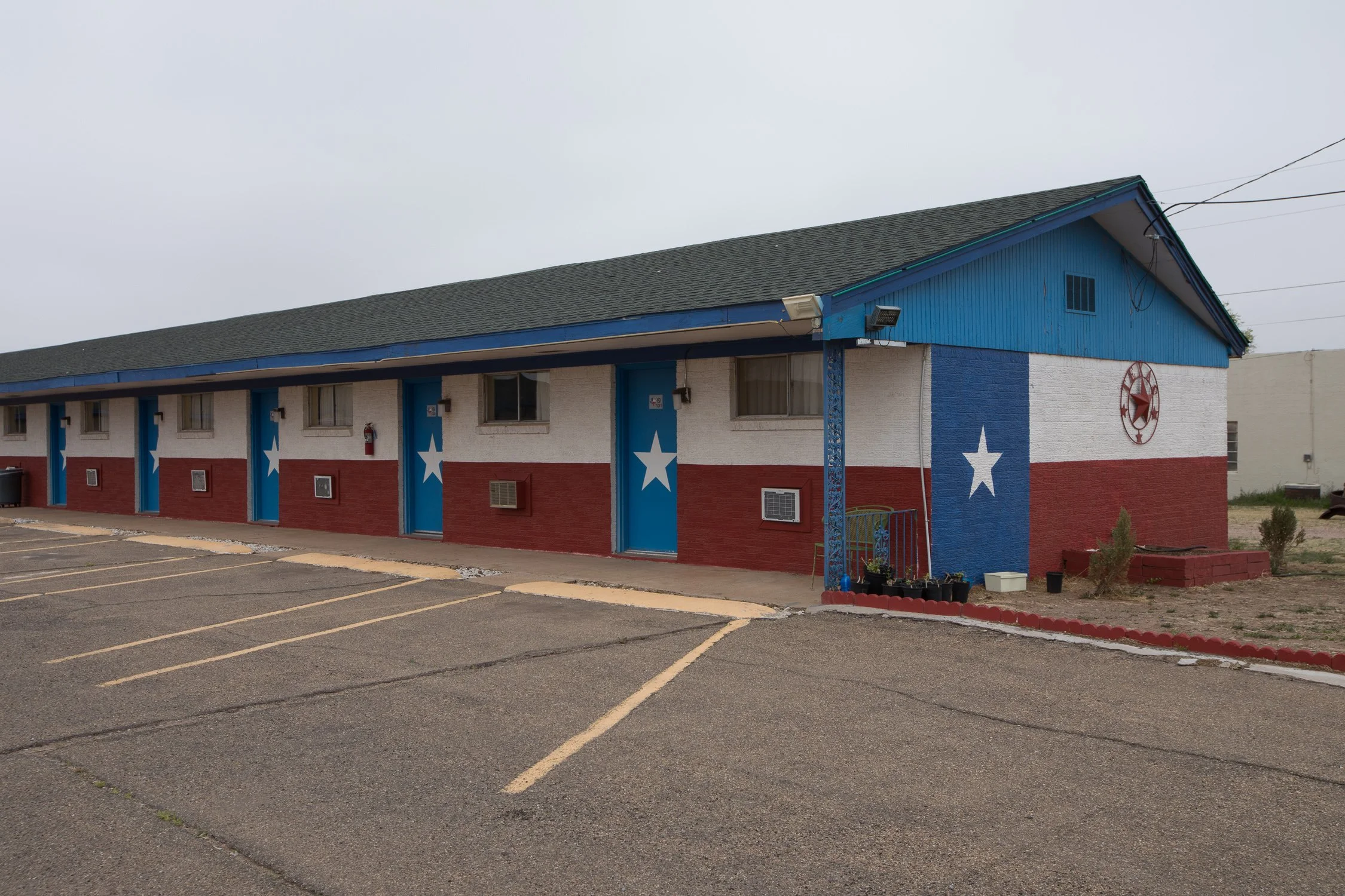 Motel azul con banderas de Texas y un estacionamiento vacío