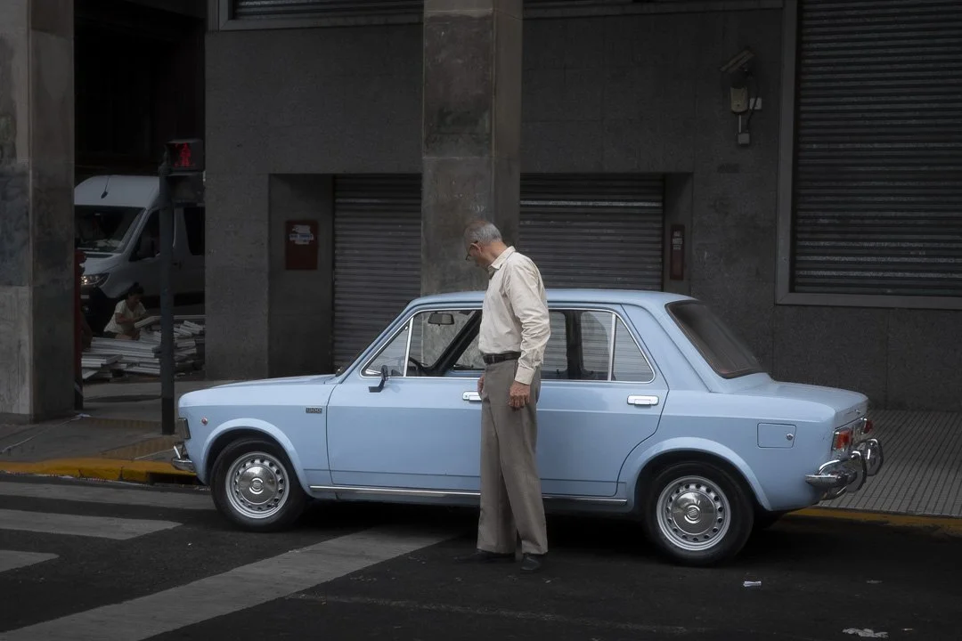 Hombre observando un auto clásico celeste estacionado en una calle de Buenos Aires, 2025
