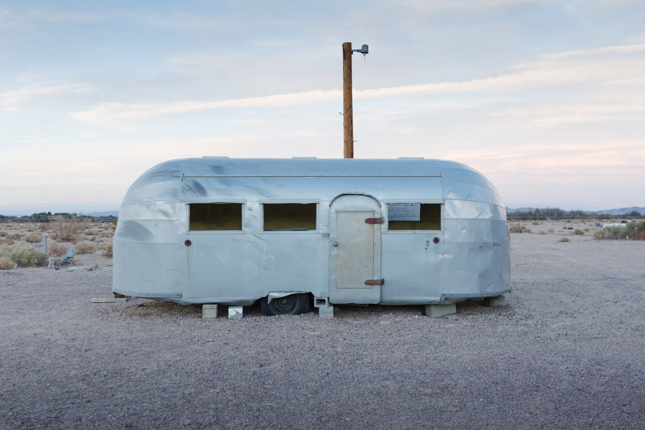 Casa rodante Airstream plateada en el desierto al atardecer