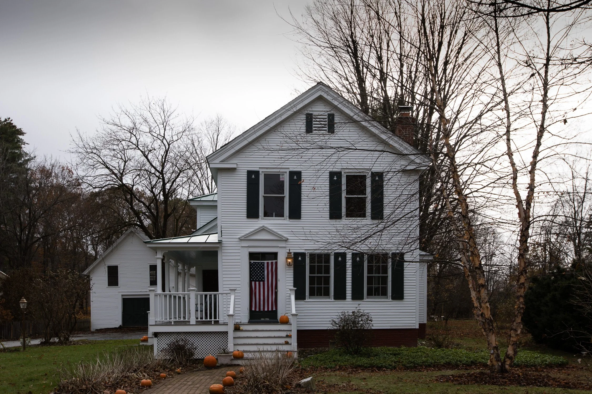 Casa de madera blanca de estilo americano entre árboles sin hojas