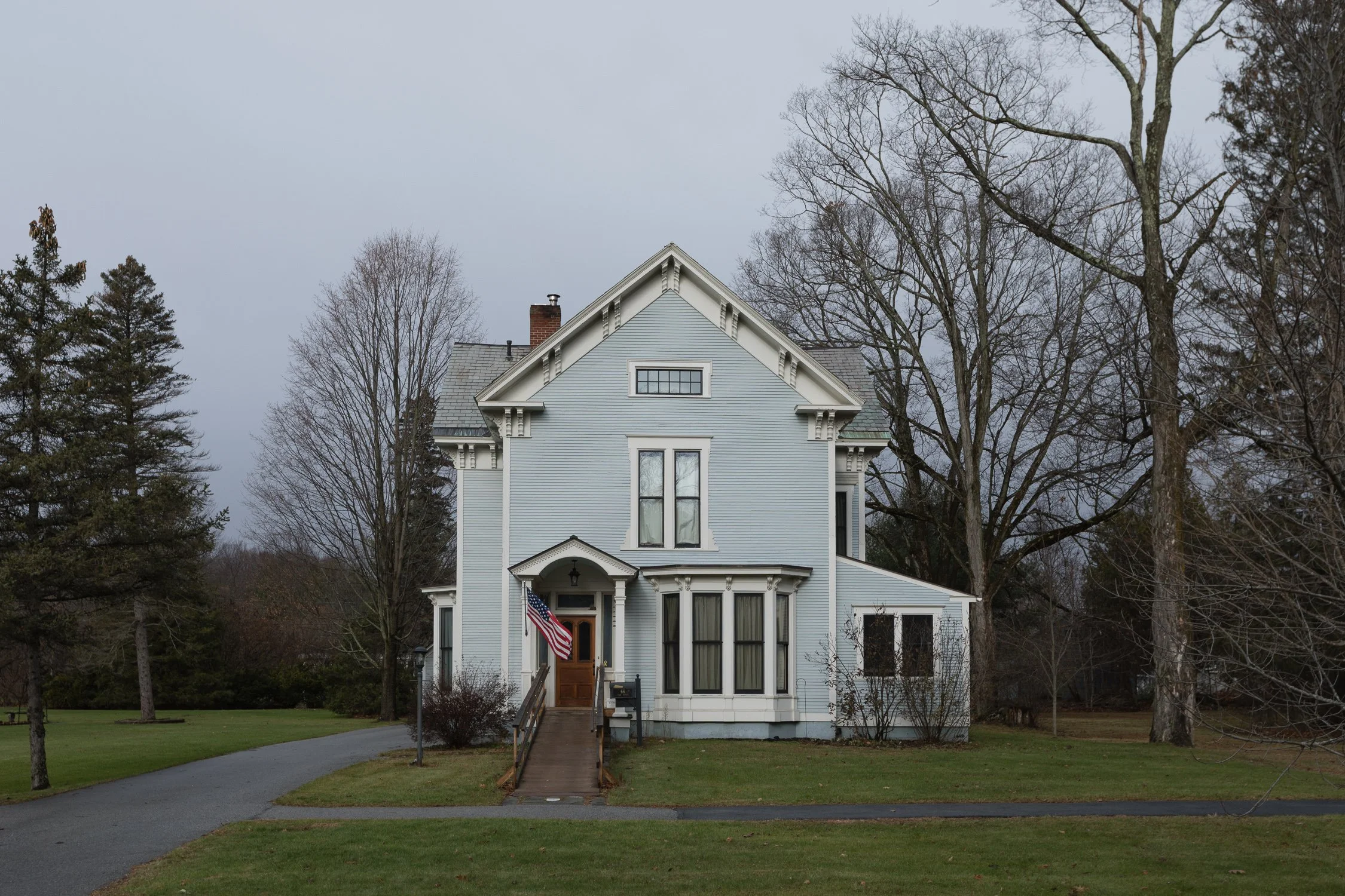 Casa victoriana blanca junto a un camino arbolado