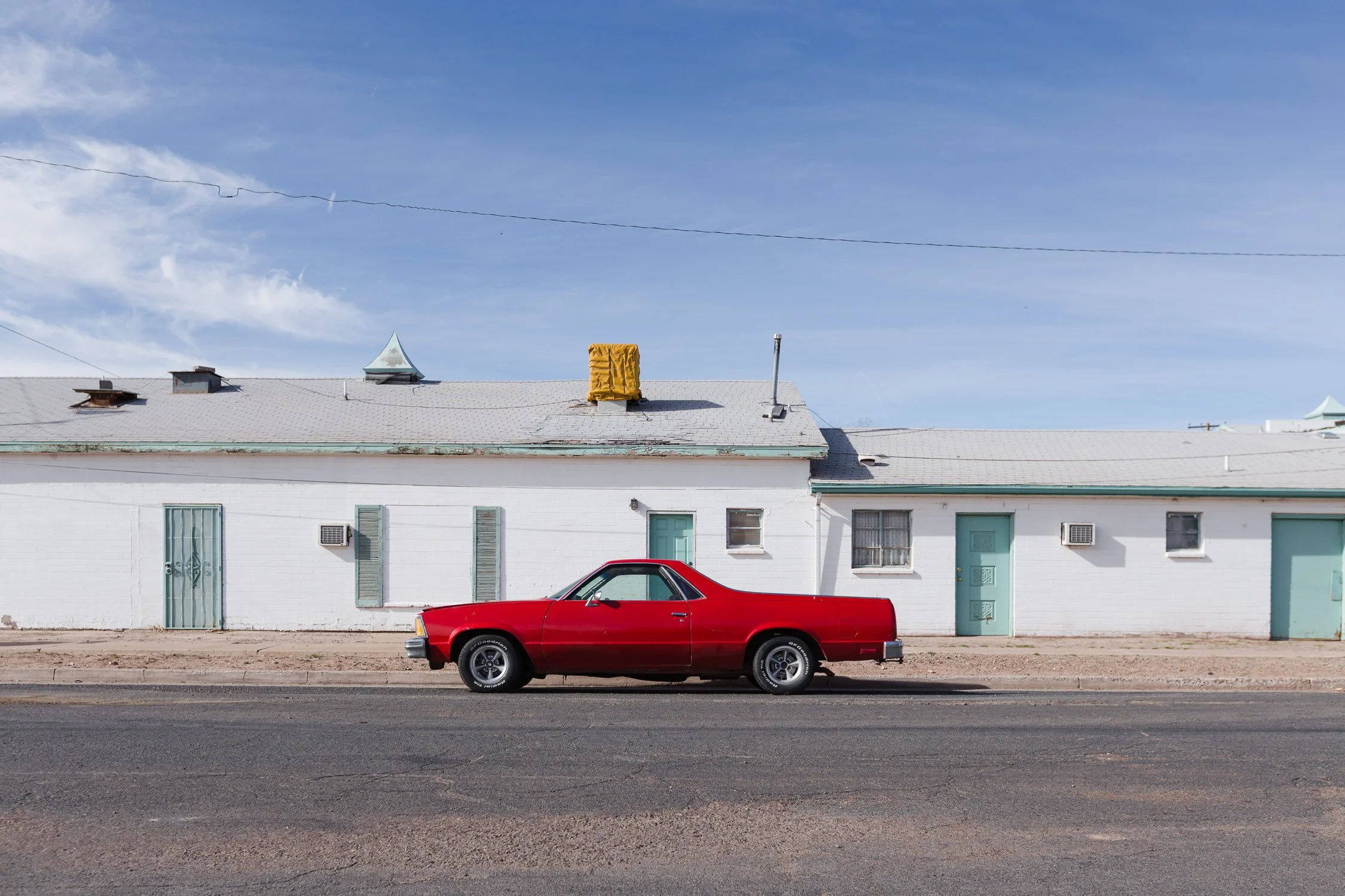 El Camino rojo estacionado frente a un motel blanco en una ruta del oeste estadounidense