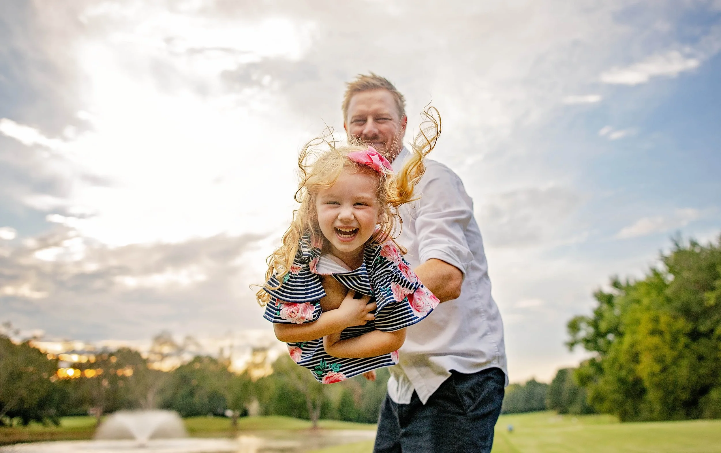 dad holding daughter in the air while both smile