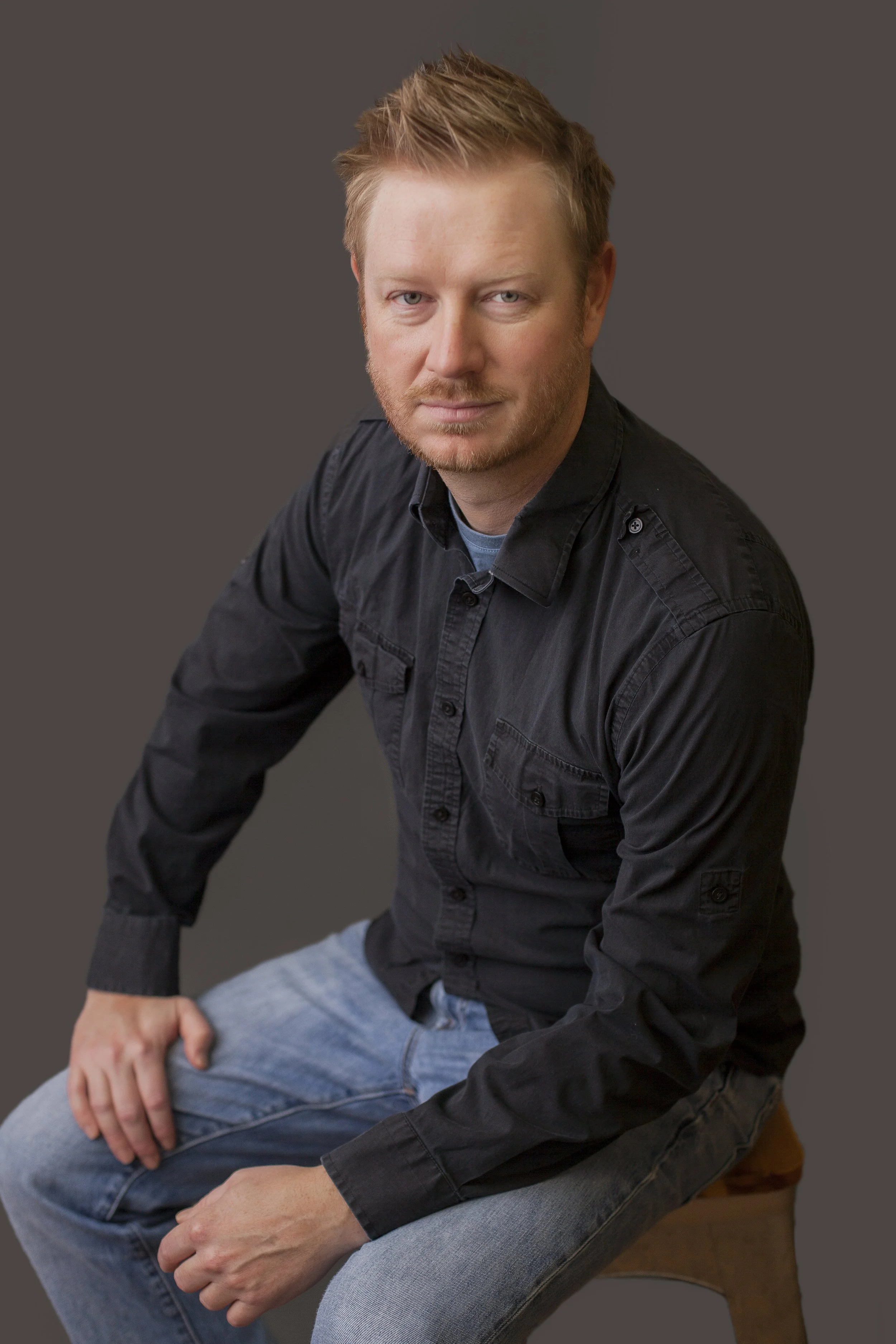 man sitting with dark background looking at camera