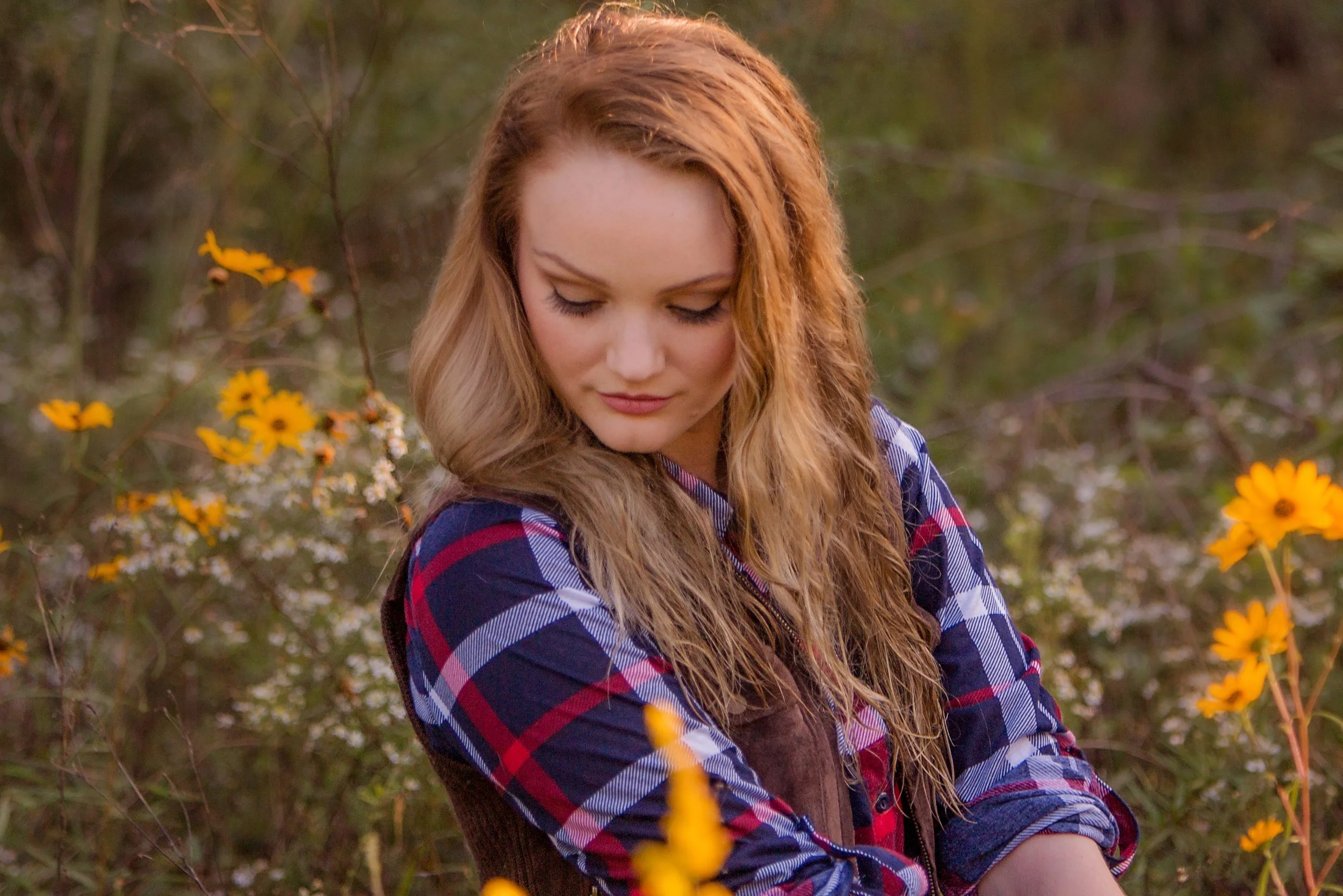 young woman looking down into a field of flowers