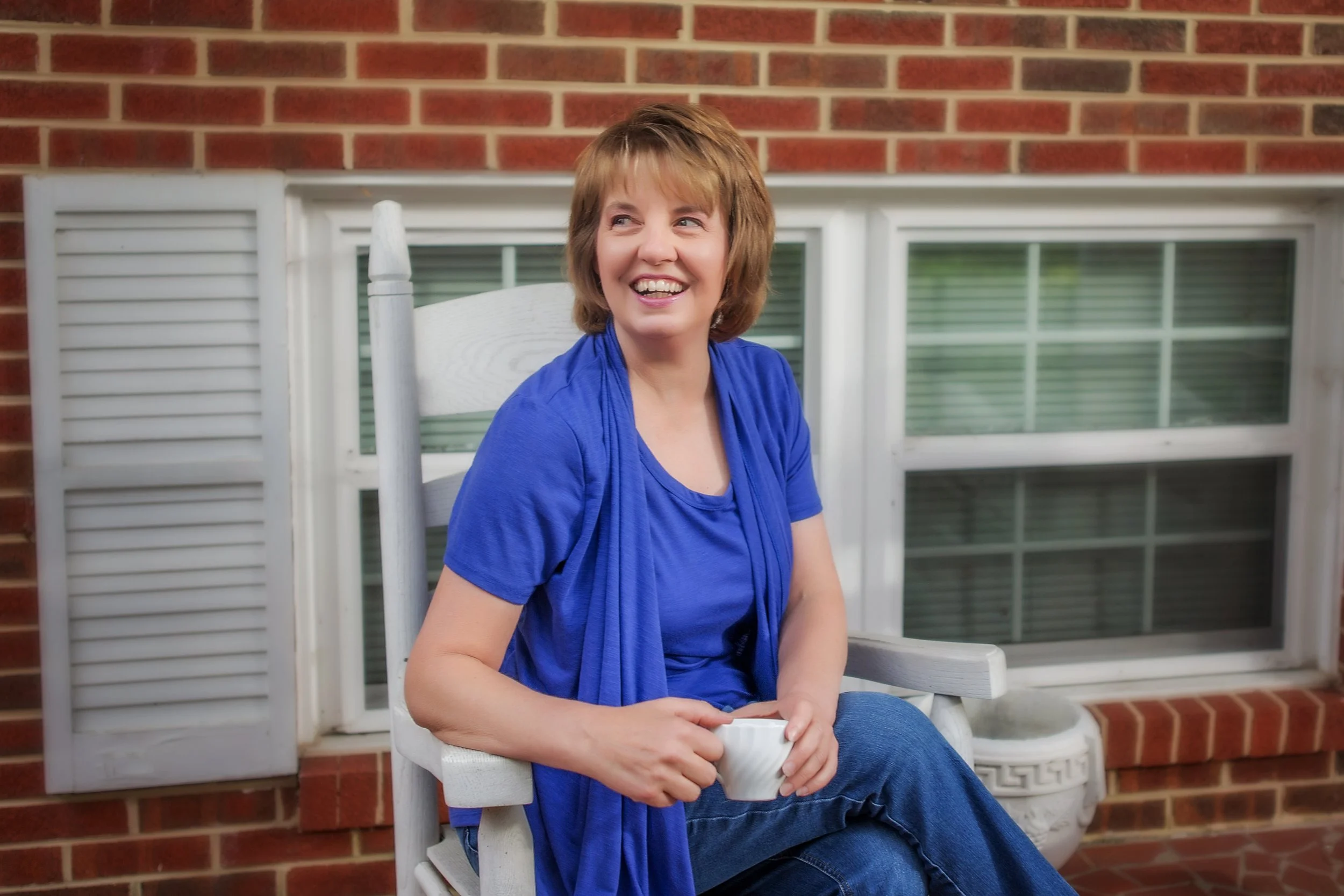 woman sitting holding coffee and smiling