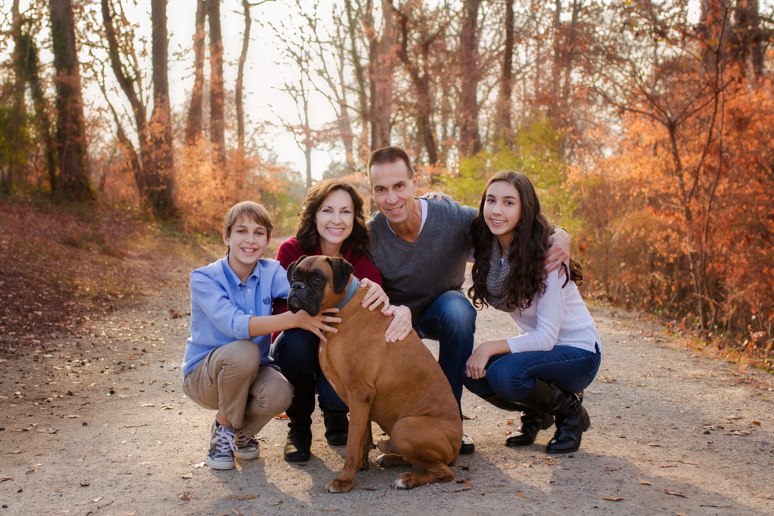 a family portrait of a mom, dad, two kids and a dog set in fall foliage scenery