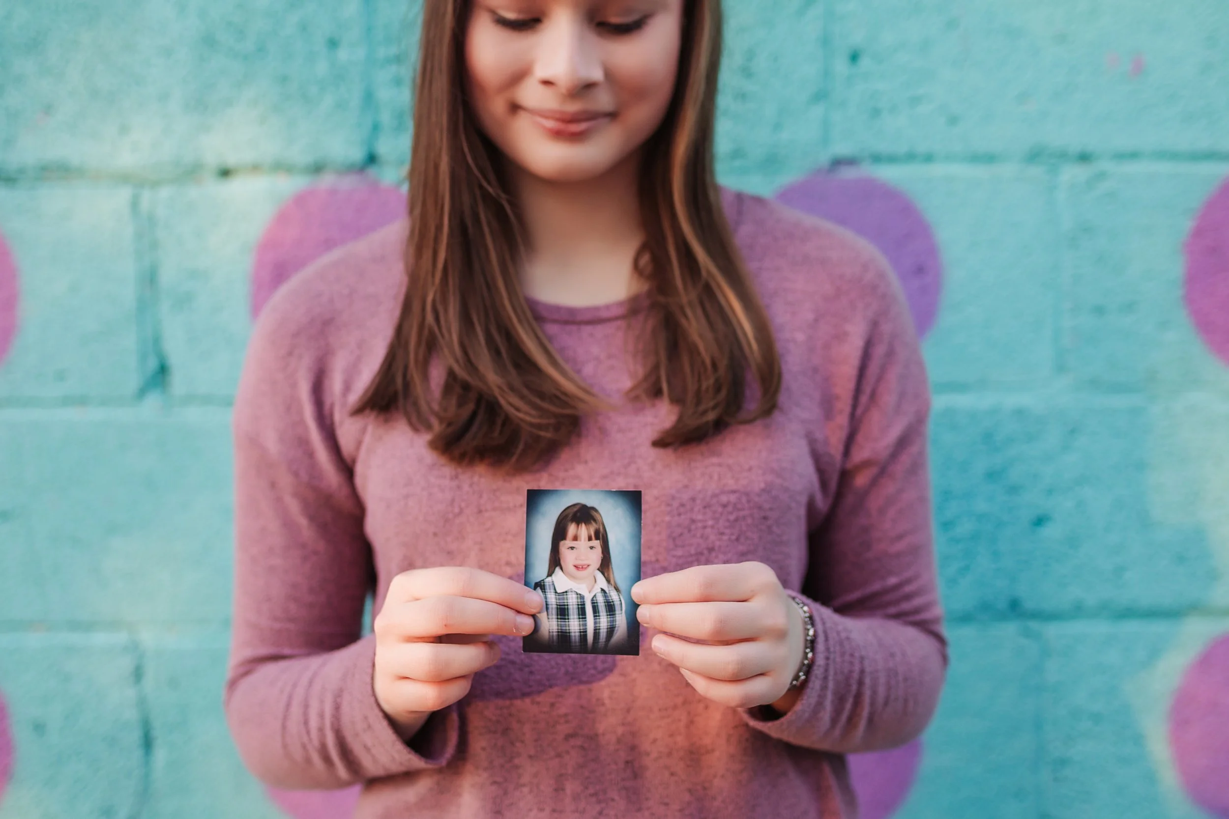 young woman looking at a photo of herself as a child