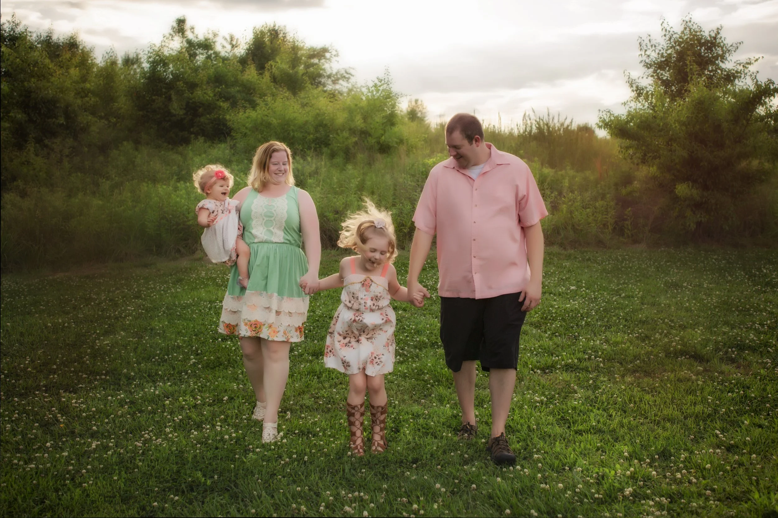 family walking through a field smiling