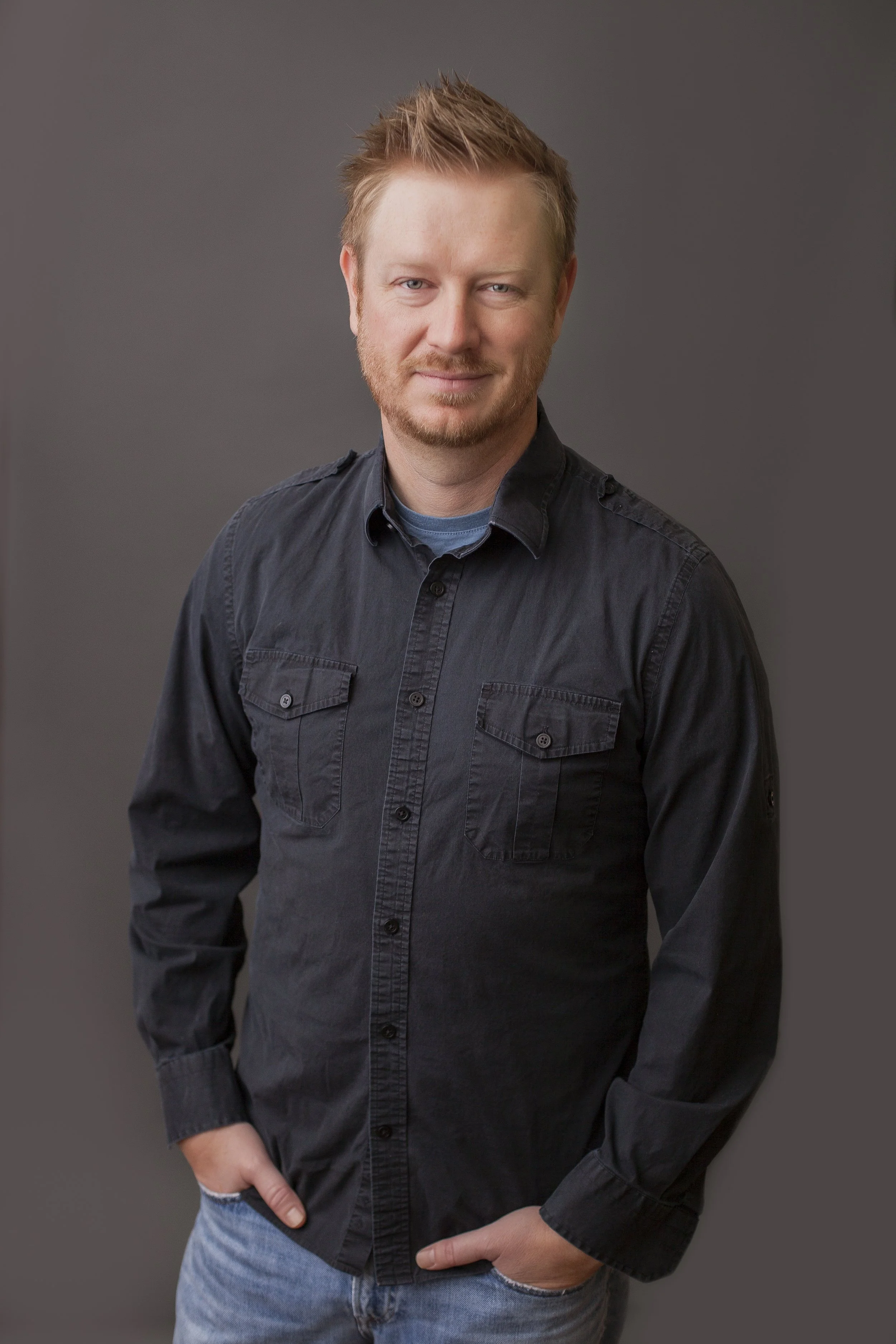 man standing with hands in pockets looking at camera