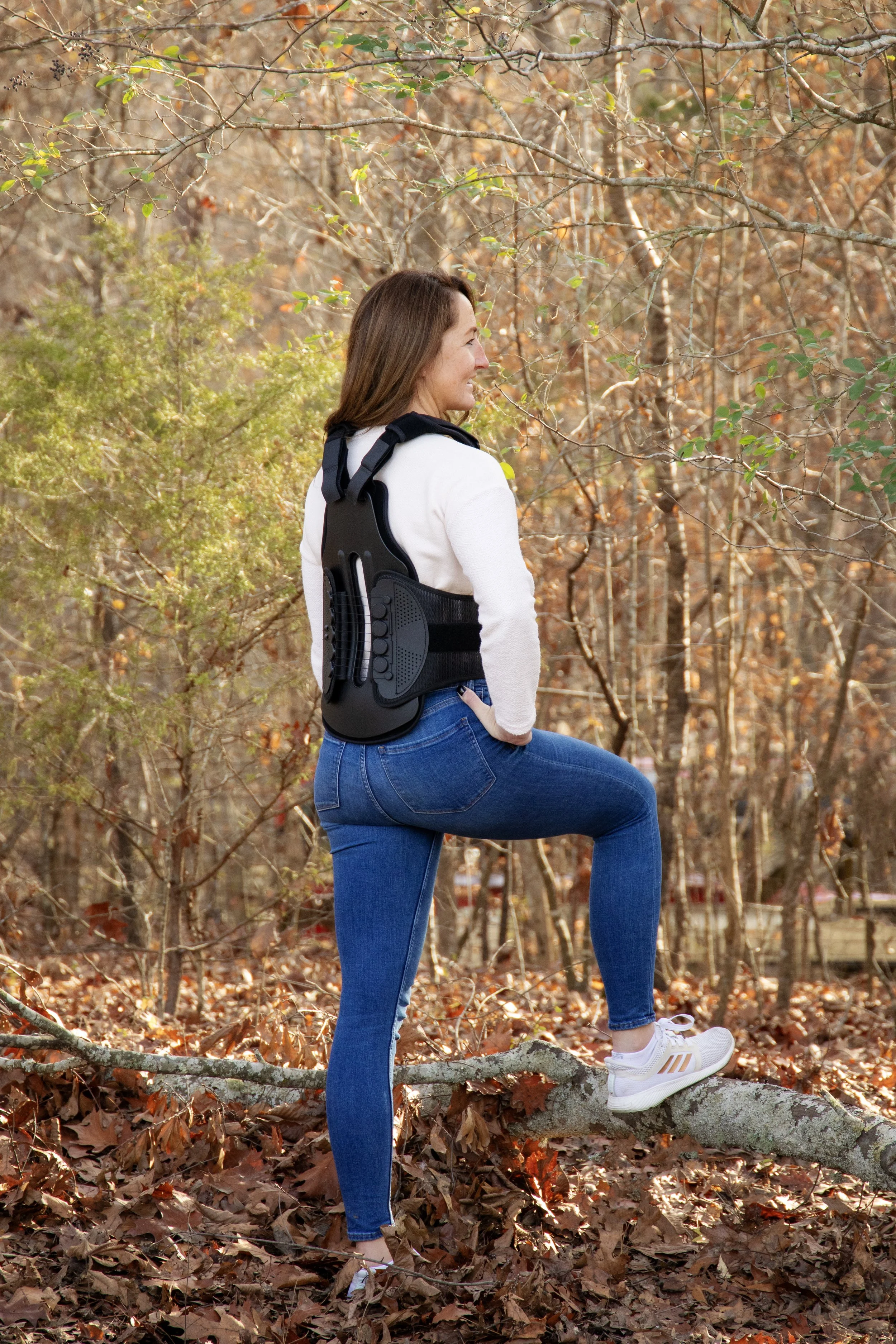 woman standing in the woods with a back brace on