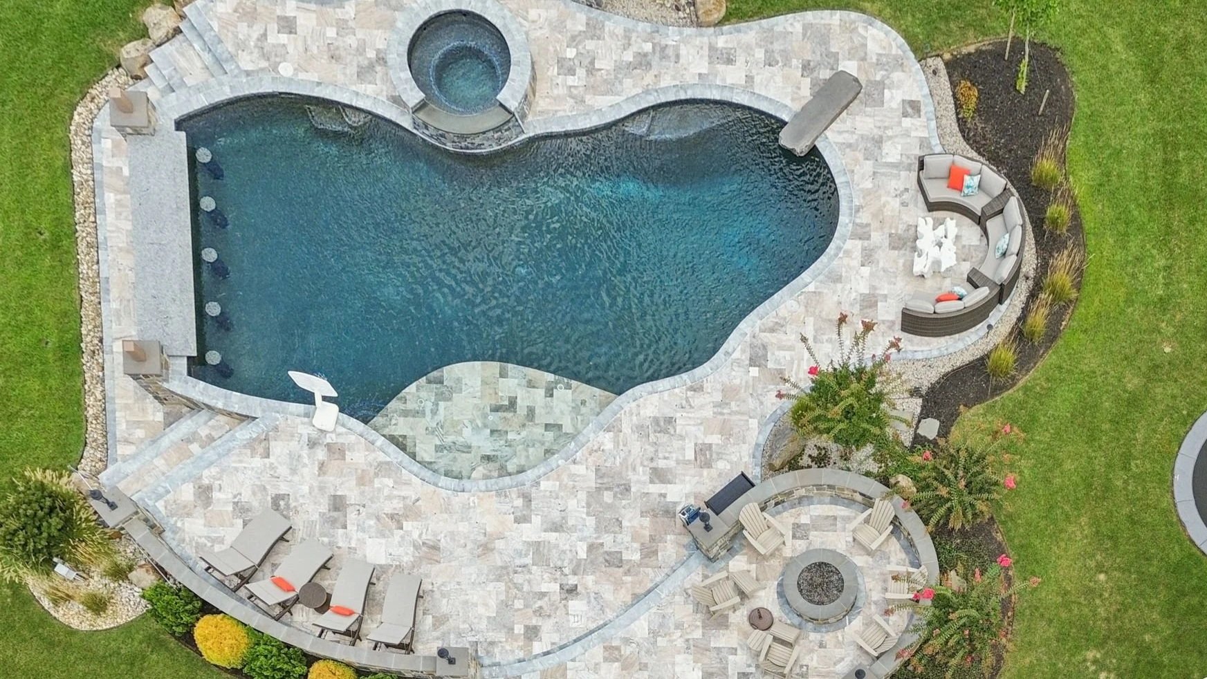 Overhead view of the freeform saltwater pool with spa, travertine patio, and fire pit seating