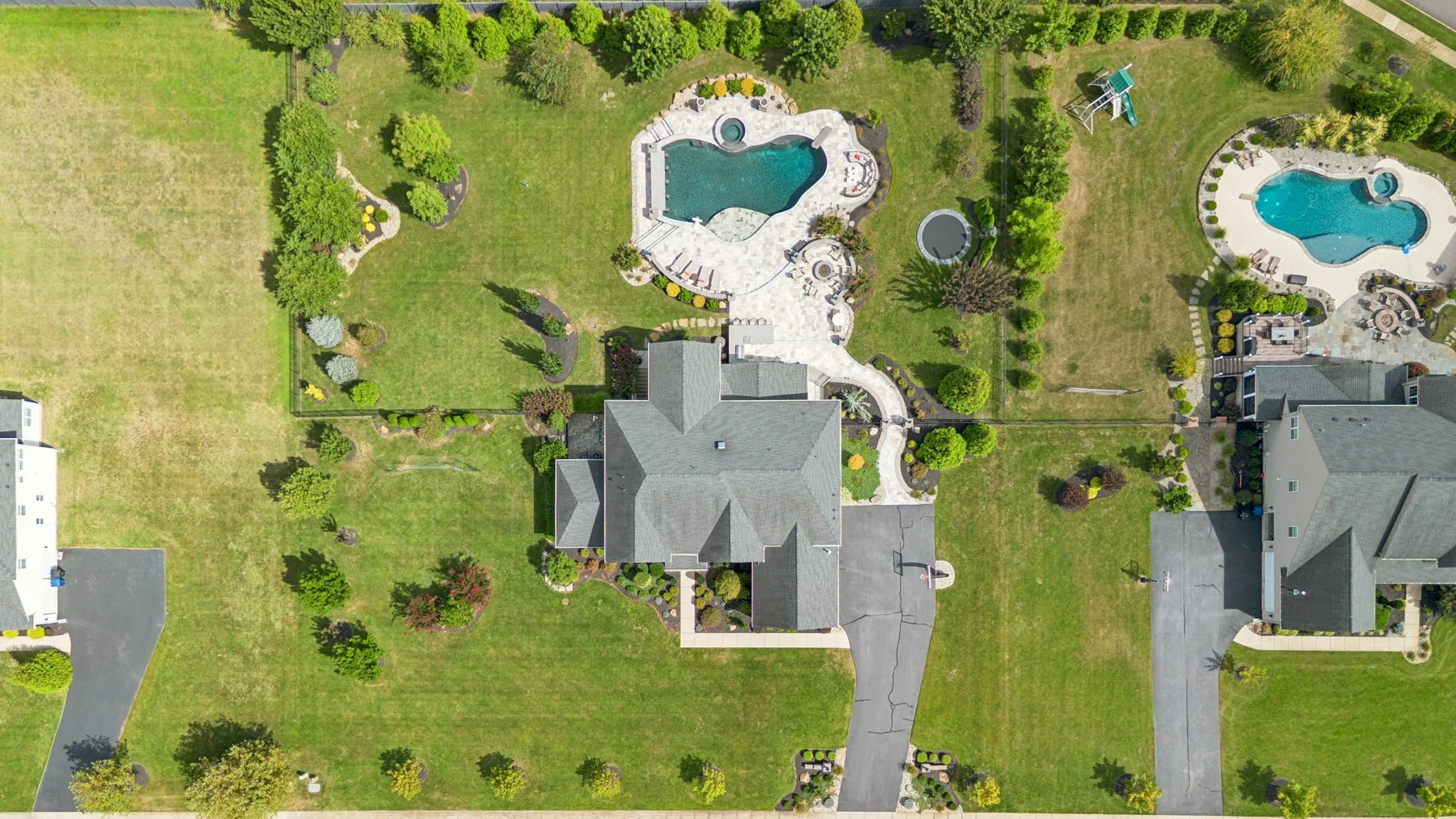 Top-down drone view of the home, driveway, saltwater pool, and full acre lot