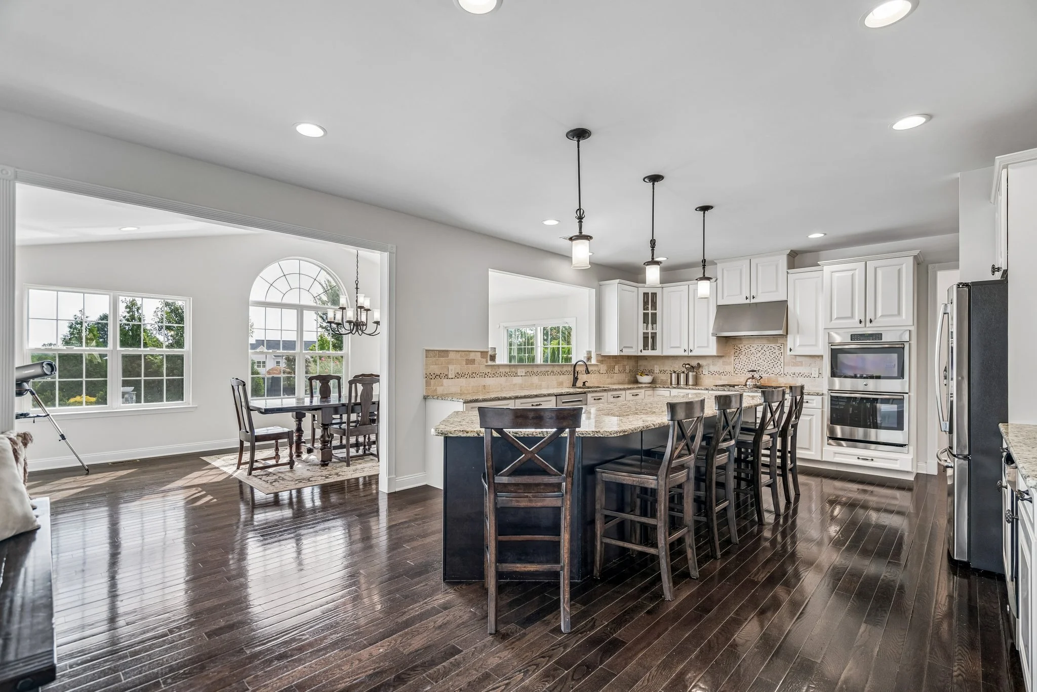 Open kitchen with a large island and bar seating, white cabinets, and stainless steel appliances