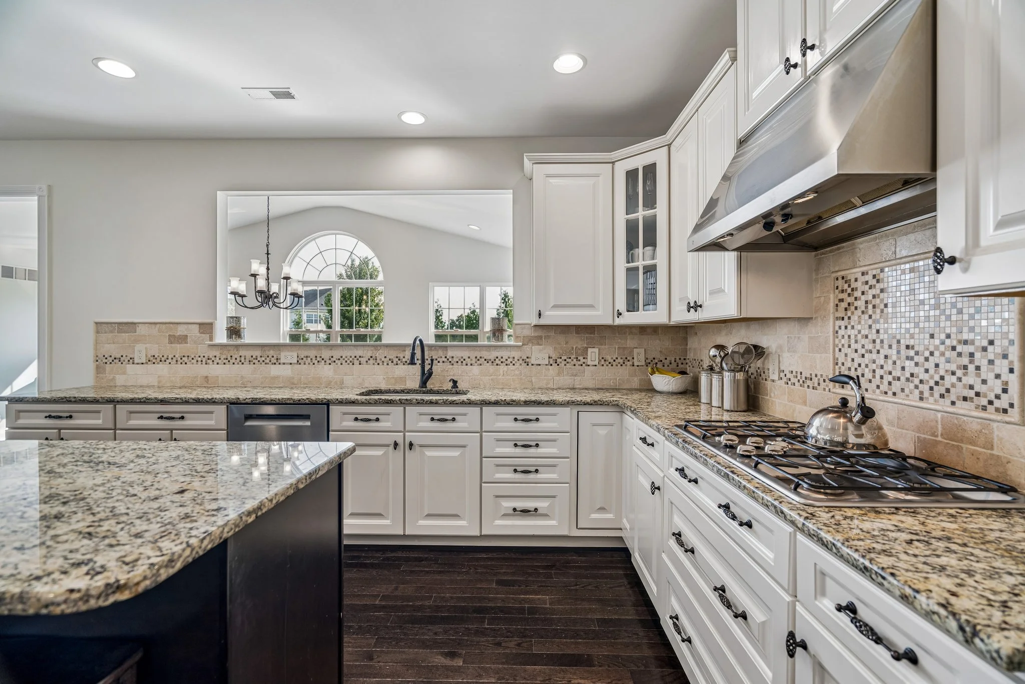 Kitchen corner with white cabinets, granite counters, a gas cooktop, and a pass-through window to the breakfast nook
